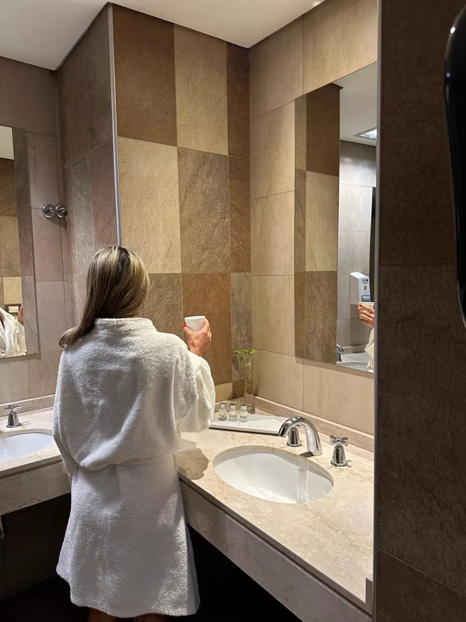 Baño moderno con paredes texturizadas y doble lavabo — proyecto Experiencia única en Del Bono Park, por ATRIM GLOBAL, en San Juan