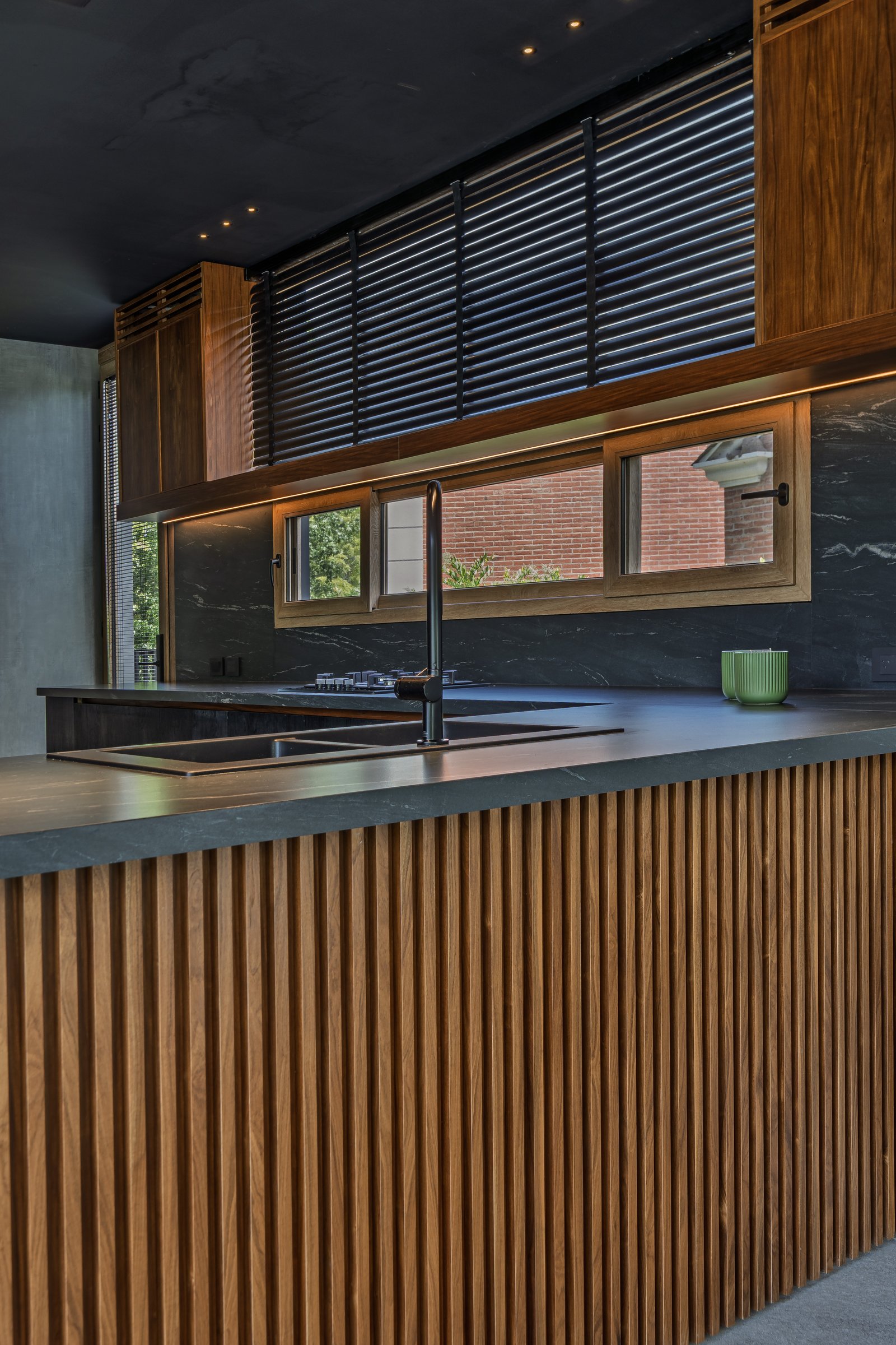 Cozinha moderna com ilha de madeira e pedra, iluminação linear — projeto Castores - Estudio Gambotto, por ABEJA CONCEPT, em Los Castores