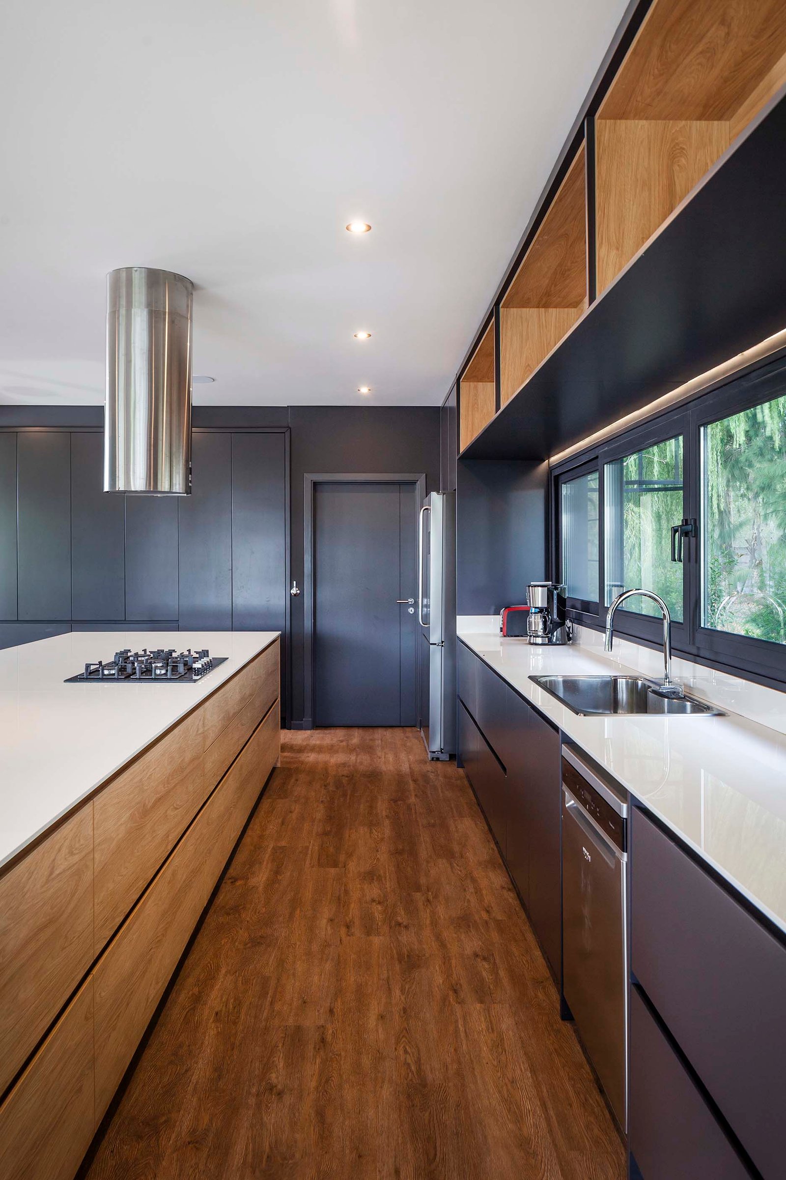 Cocina moderna con isla, madera natural y gabinetes oscuros — proyecto CASA T199, por A'PRIMA - Arquitectura Sustentable, en Los Robles 5901