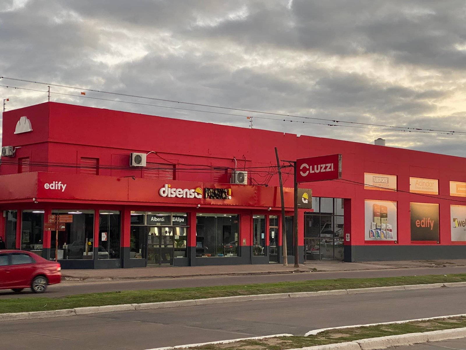 Fachada comercial roja con vidrieras amplias — proyecto Edify Casa central. Local de venta de materiales de Construccion., por Arquitecto Gustavo Maidana, en Corrientes