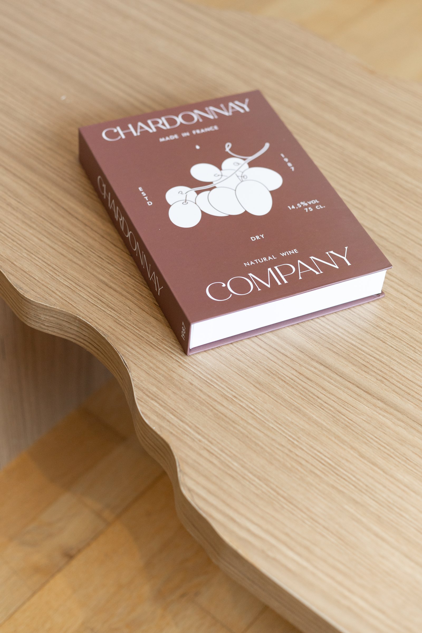 Libro de chardonnay sobre mueble de madera con borde ondulado — proyecto Rio, por Martina Kleinert, en Saavedra