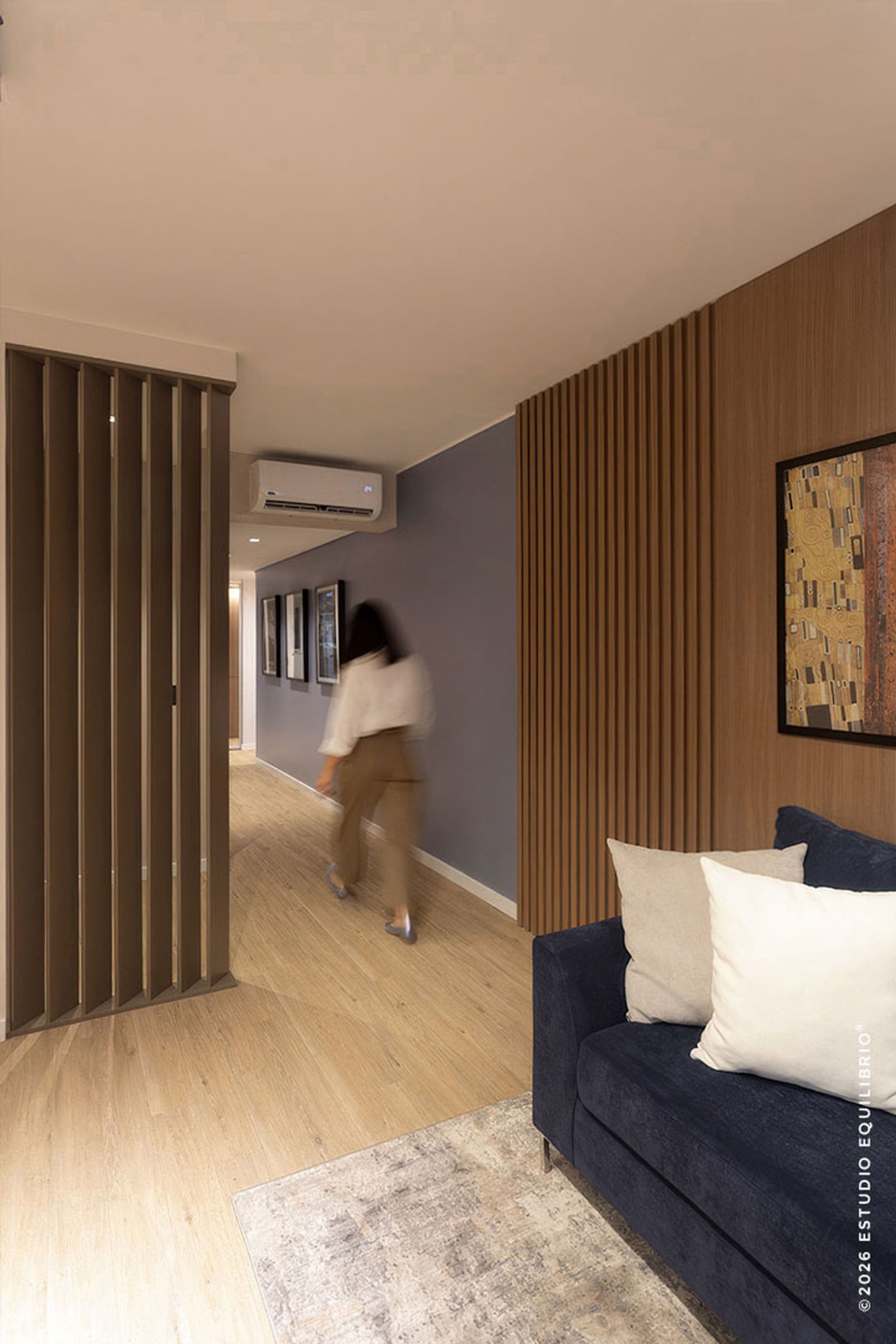 Corredor moderno com parede de ripas de madeira e sofá azul — projeto Proyecto Zapiola, por Estudio Equilibrio, em Belgrano