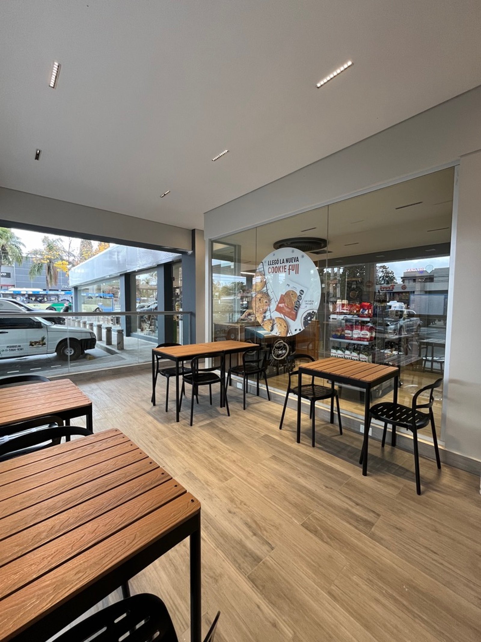 Cafetería moderna con mesas de madera y metal, piso de madera clara — proyecto Full YPF Muniz, por Arcucci Arquitectura, en Muñiz