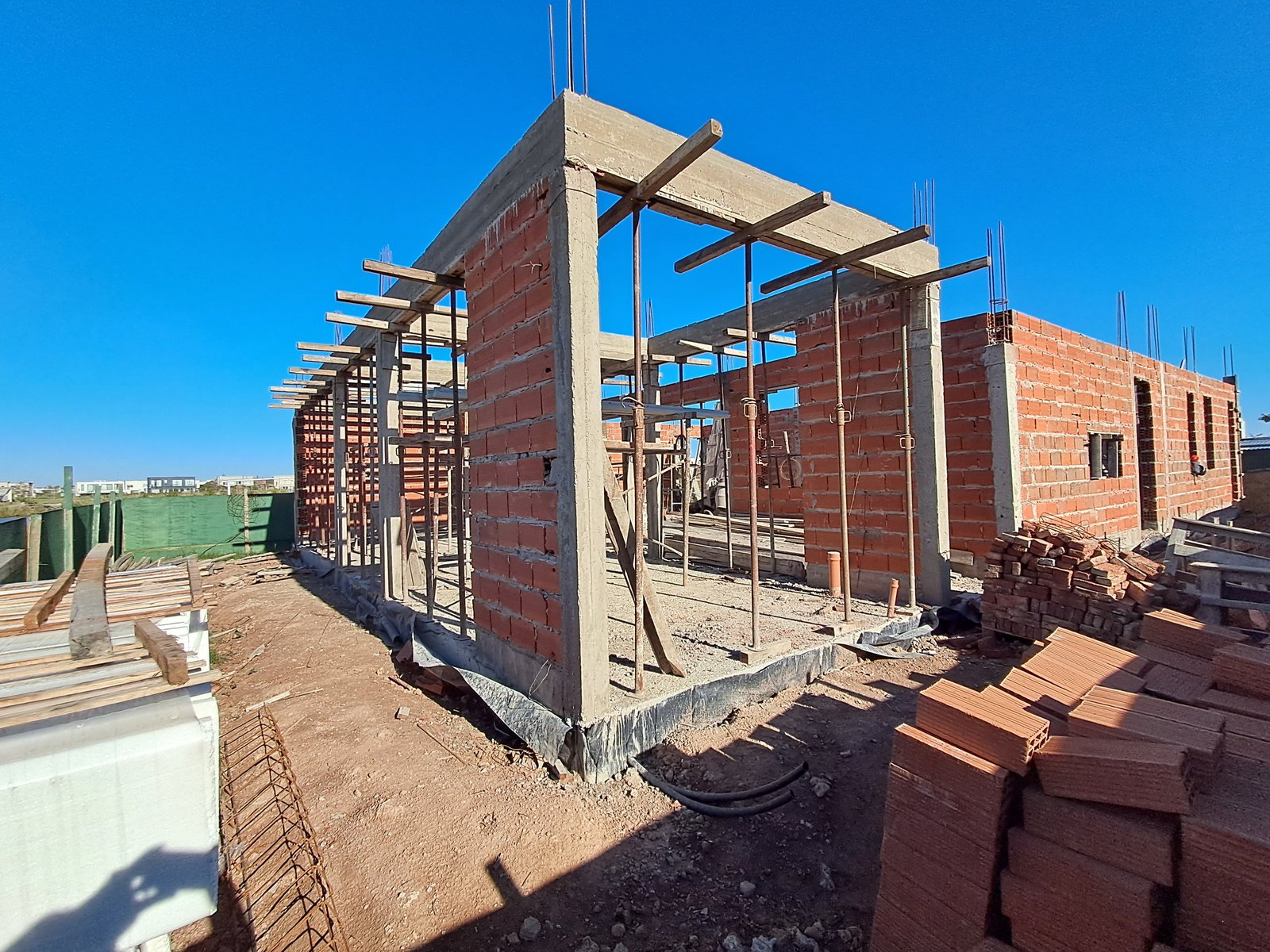 casa en construcción con ladrillos expuestos y vigas — proyecto RIBERAS  332, por IRALA CONSTRUCCIONES, en Belén de Escobar
