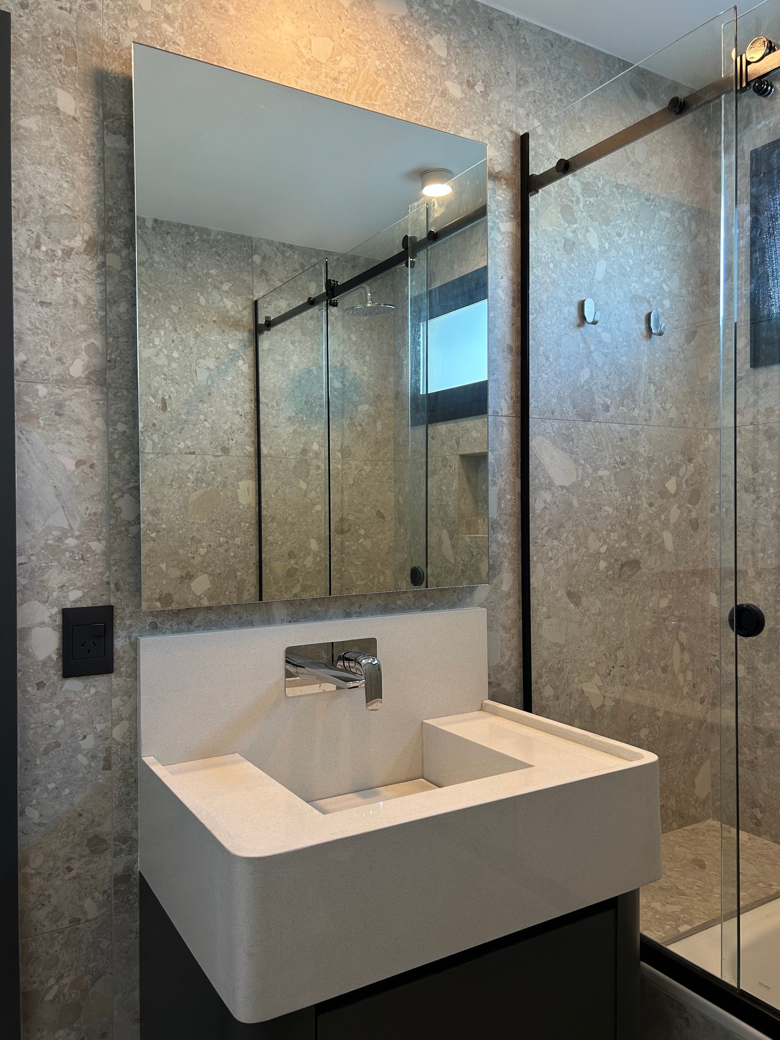 Banheiro moderno com grandes azulejos de pedra cinza, pia de pedra branca e box de vidro — projeto LIBERTADOR II, por ESTUDIO TEZ, em Palermo