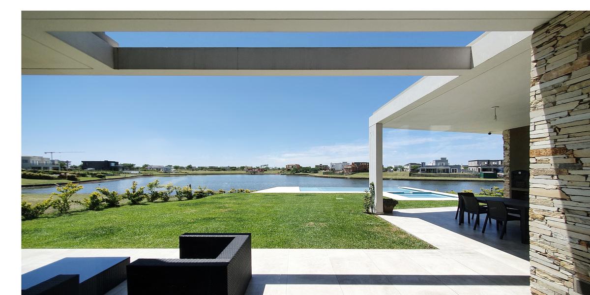 Pátio moderno com vista para o lago e móveis externos — projeto CASA PUERTOS, por ABAD GADANO, em Belén de Escobar