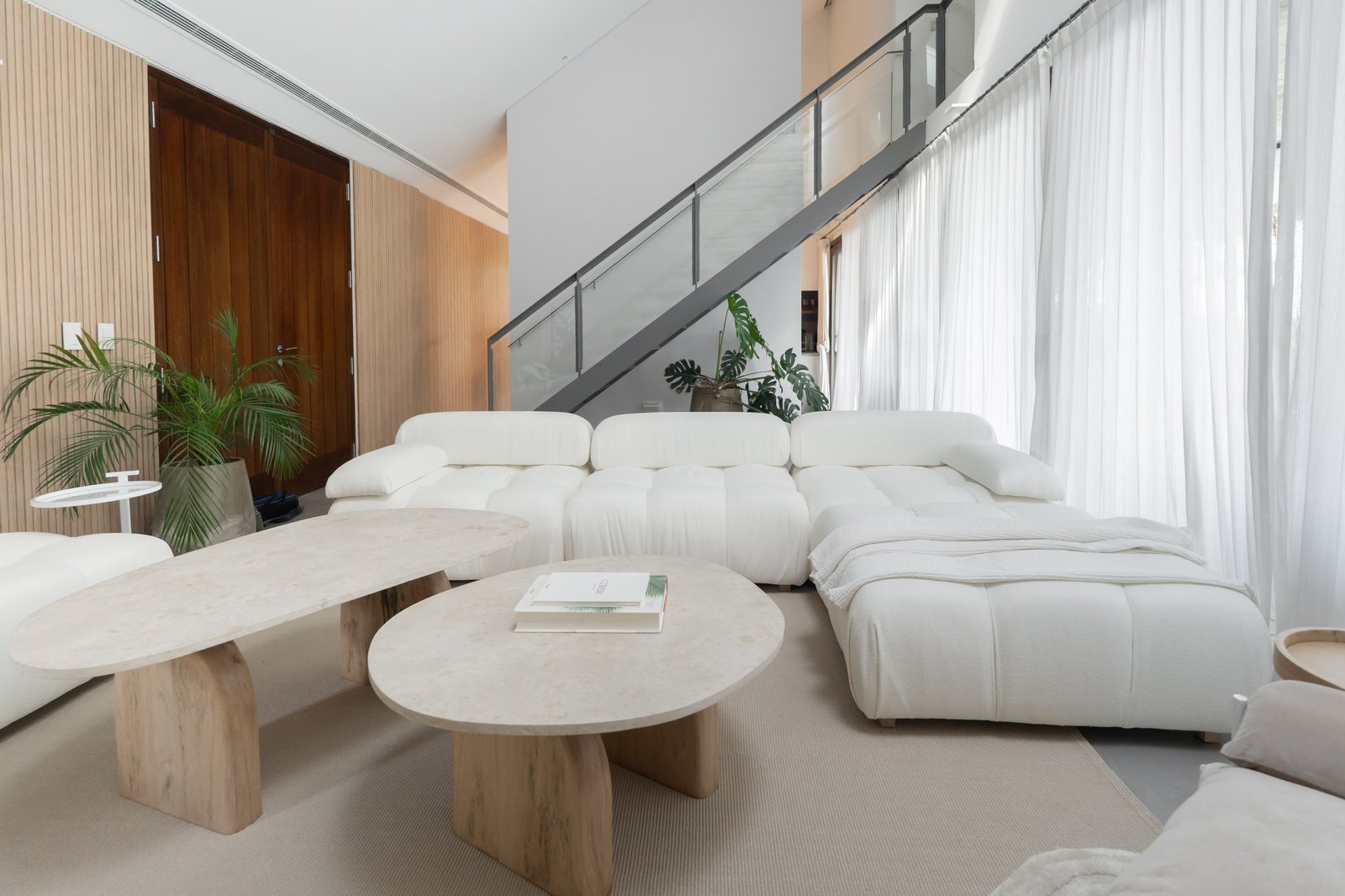 Sala de estar moderna com sofá curvo branco e escada flutuante — projeto PROYECTO NAUDIR, por July Acosta Home, em Belén de Escobar