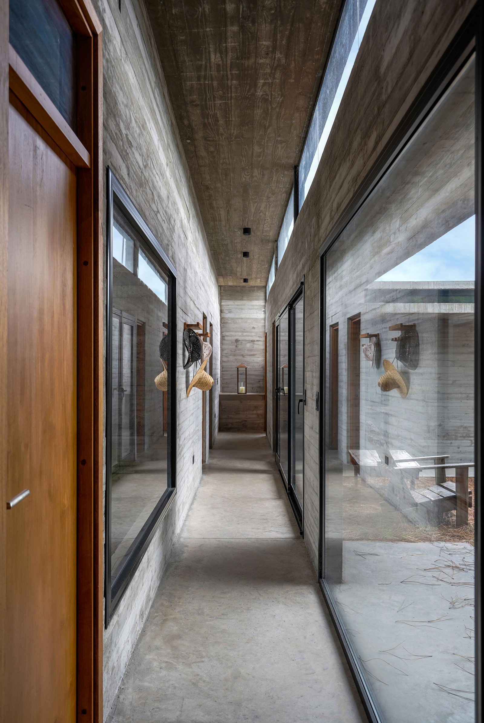 Pasillo de hormigón visto con grandes ventanales y luz natural — proyecto Casa Loma, por Besonías Almeida arquitectos, en X6VF+67