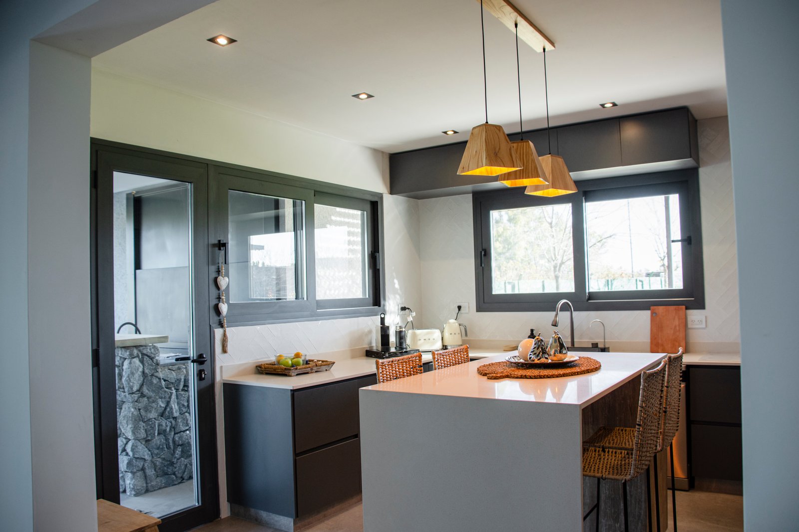 Cozinha e sala de jantar modernas integradas, ilha e detalhes em madeira — projeto Casa Tipas, por MSMC, em Сармьенто 3830