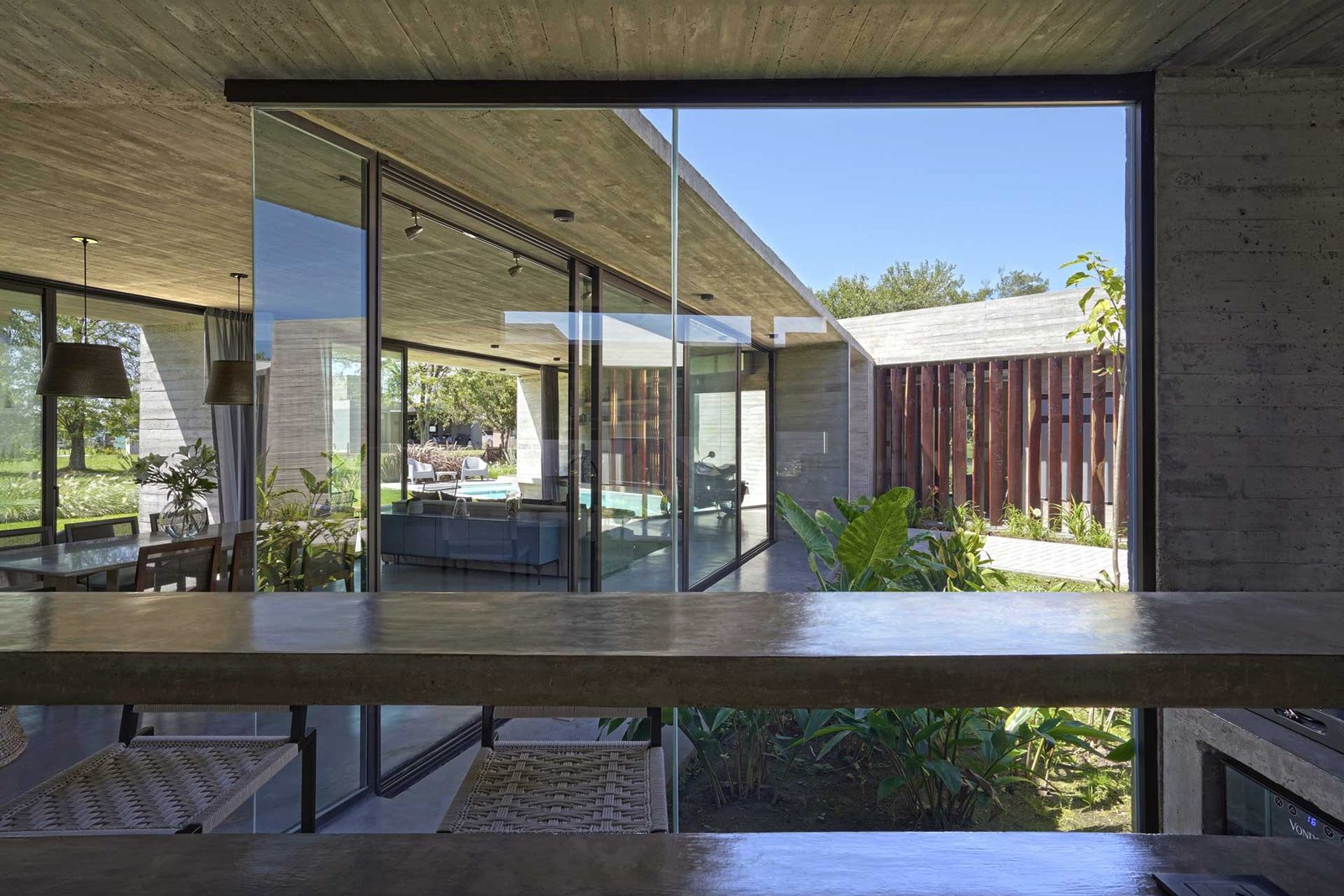 Living moderno de hormigón visto con patio interior exuberante — proyecto Casa Pau, por Besonías Almeida arquitectos, en Guillermo Enrique Hudson