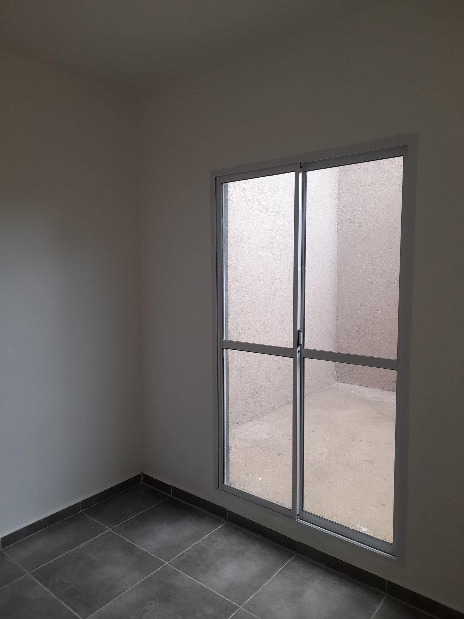 Pasillo interior moderno con puerta corrediza de vidrio y suelo de baldosa gris — proyecto Departamentos, por CN Construcciones, en Alta Gracia