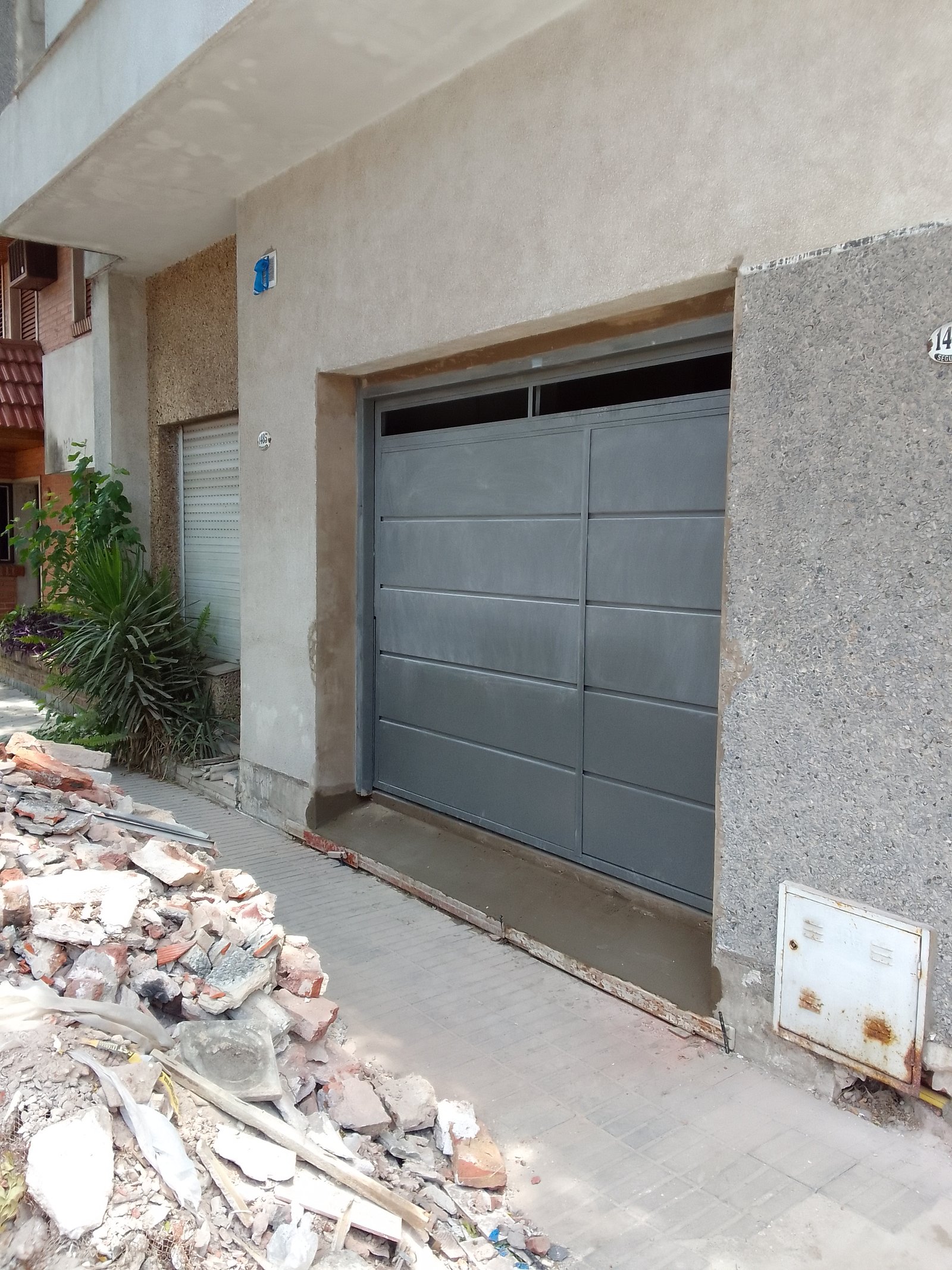 Fachada de casa com porta de garagem cinza em construção — projeto 2 Casas en Lanus, por Arquitecto Guido Niccoli, em B1824 Lanús