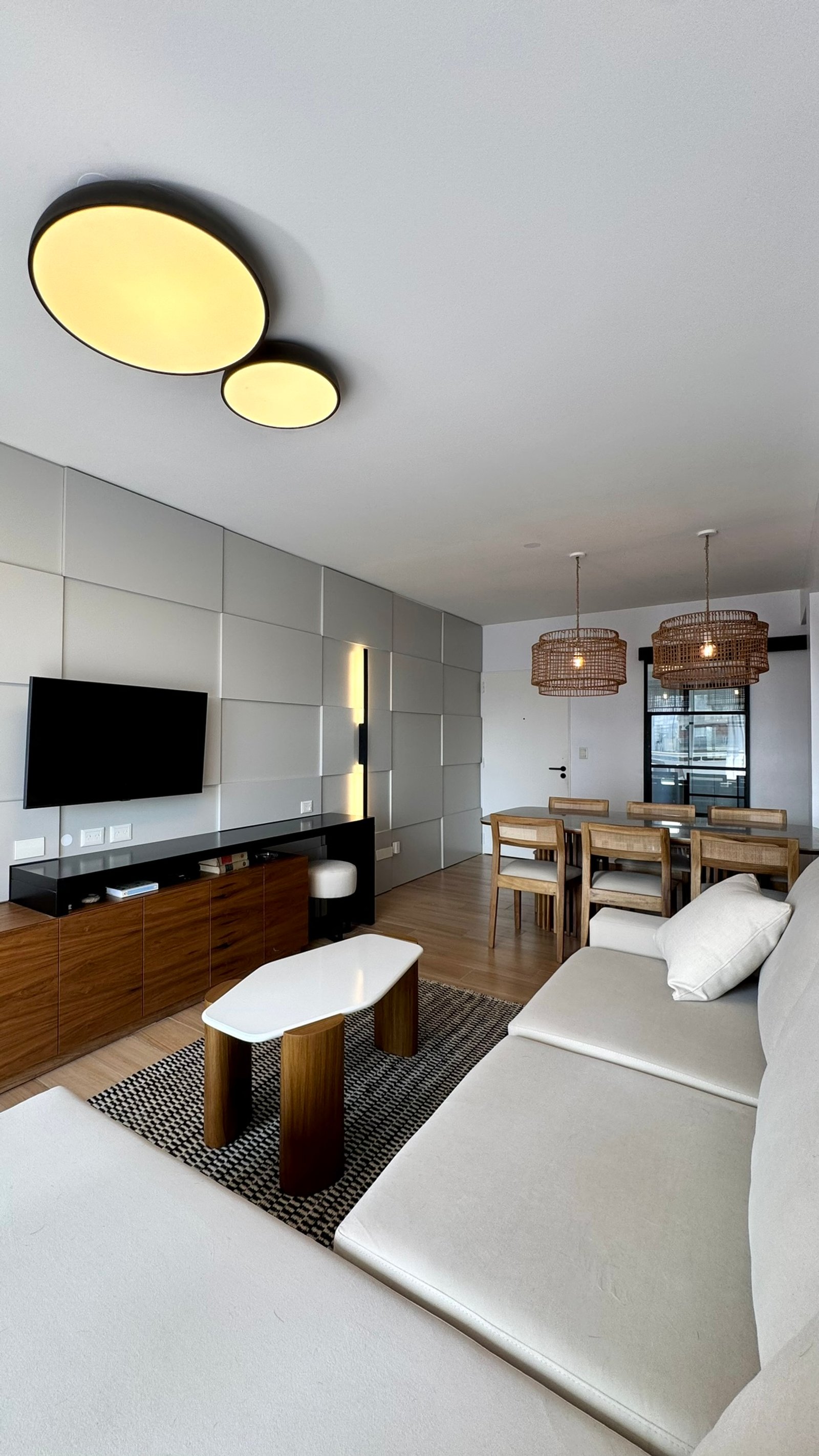 Sala de jantar e estar moderna com sofá branco, mesa de centro oval e luminárias de rattan — projeto Arengreen, por MDBK Arquitectura, em Caballito