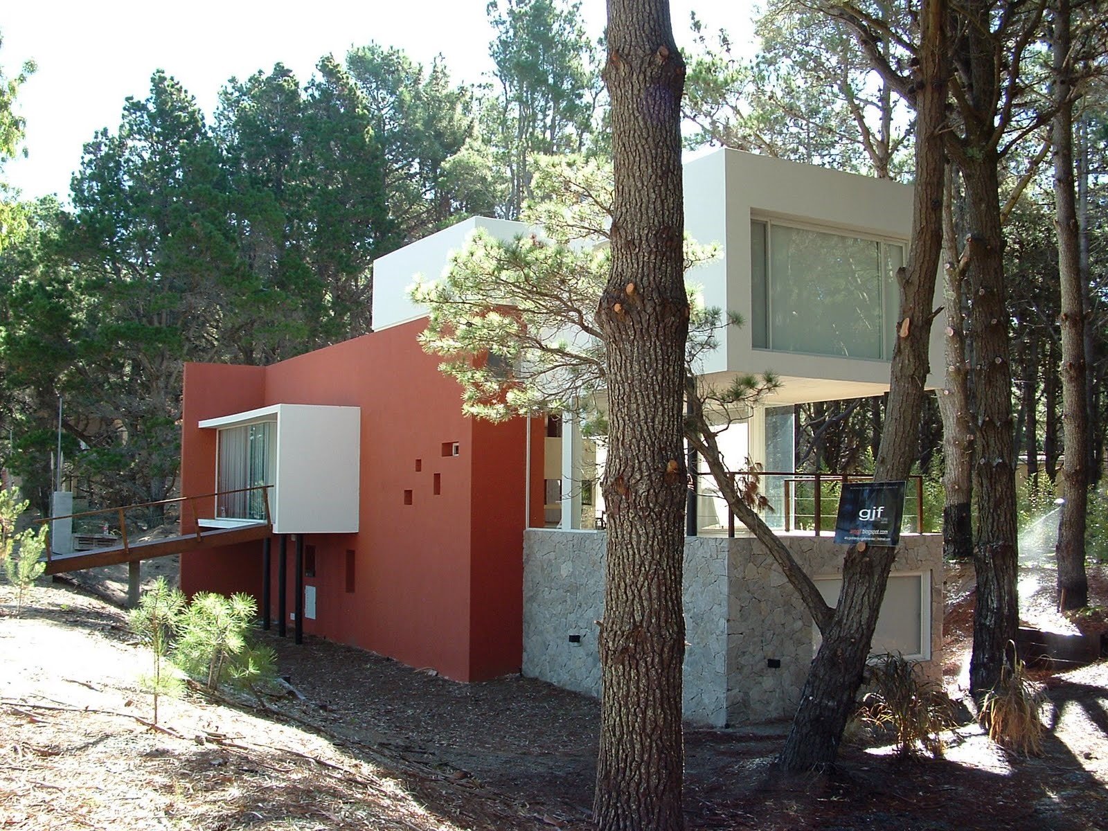 Casa moderna integrada à floresta com fachada vibrante — projeto villa del puente, por GJF estudio, em Costa del Este