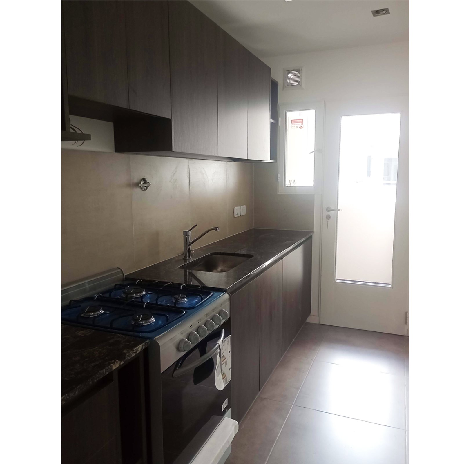 Cocina moderna con muebles de madera oscura y mesada de piedra negra — proyecto Edificio Nicasio Oroño, por ASIA - arquitectura, en Caballito
