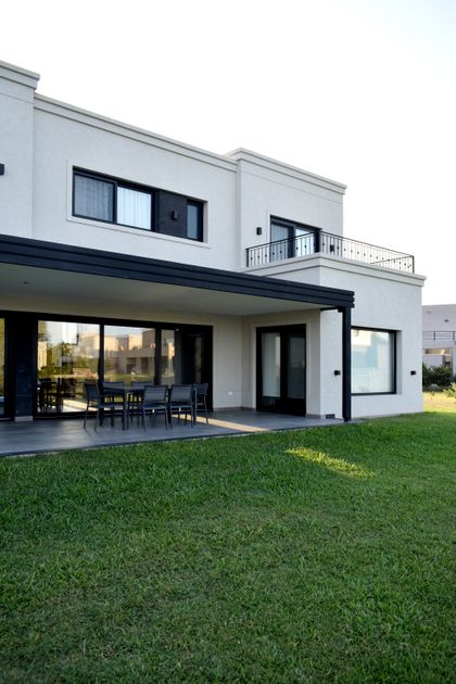 Fachada moderna con patio, césped y cielo despejado — proyecto Casa CG191, por EZ architects, en Belén de Escobar