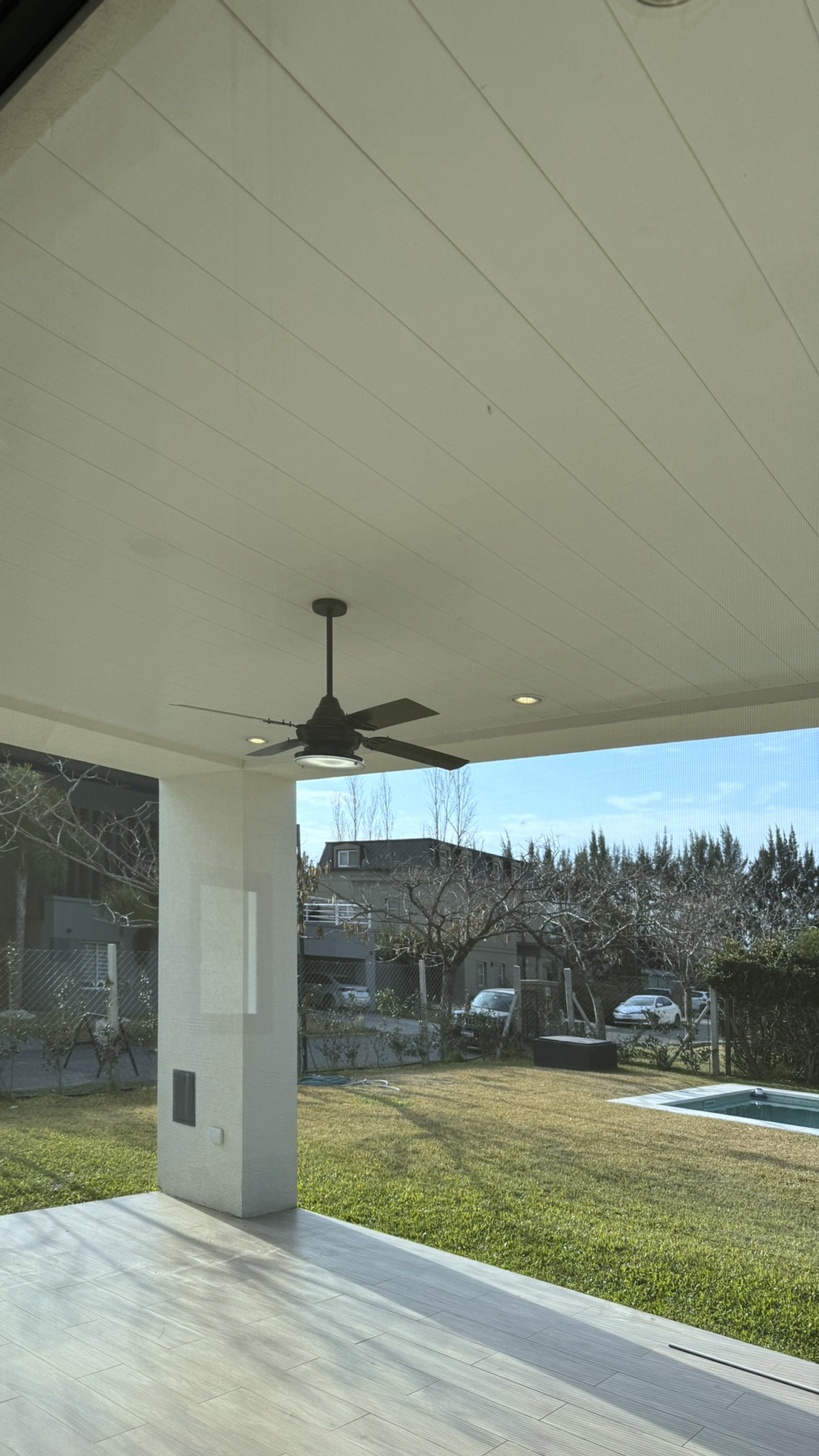 Pérgola moderna com ventilador de teto e vista para jardim e piscina — projeto Casa MC, por Hermann Arquitectos, em Bv. Central