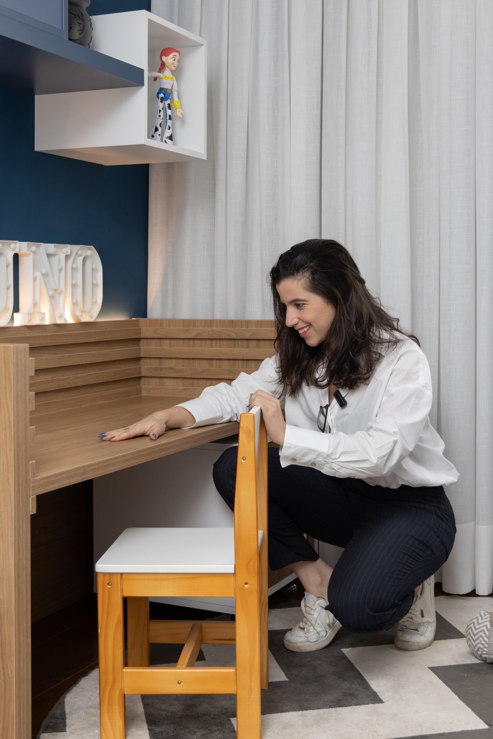 Mulher em escritório com escrivaninha de madeira e cadeira — projeto Dormitório do Nuno, por EBBA Arquitetura, em Ipiranga