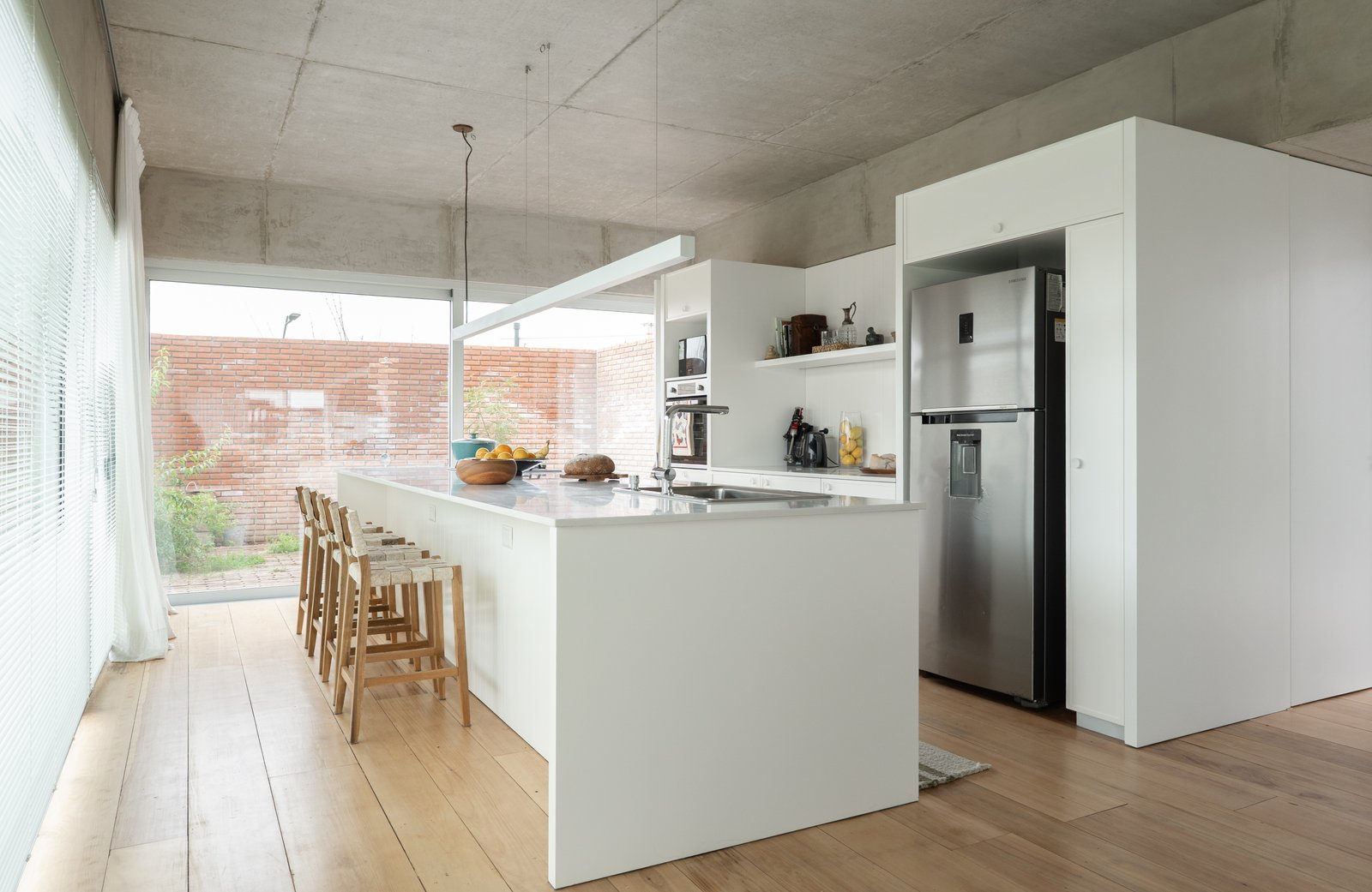 Cocina moderna abierta con isla blanca y techo de hormigón — proyecto Carpinchos, por LACROZE DESIGN STUDIO, en Nordelta