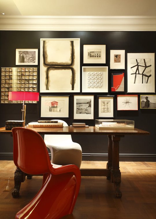 Oficina contemporánea con escritorio madera, silla roja y galería arte negro — proyecto Casa Cor 2009, por Patrícia Marinho Arquitetura 