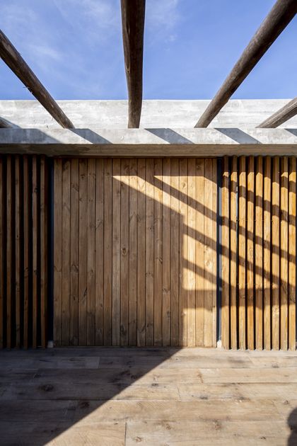Galería con pergola de vigas de madera y deck de piso de madera clara — proyecto Casa ES, por Facundo Arana Arquitecto