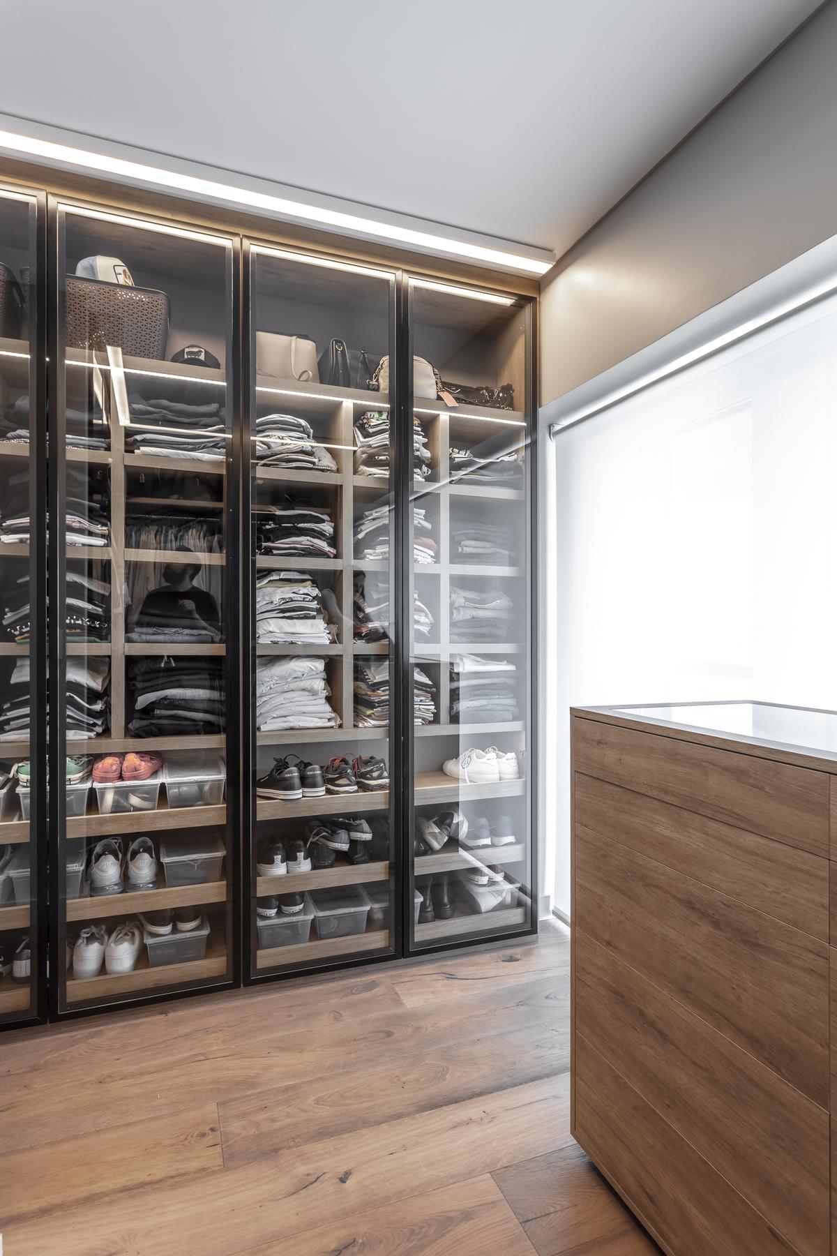 Closet moderno com prateleiras de vidro e iluminação quente — projeto SD, por Judith Babour