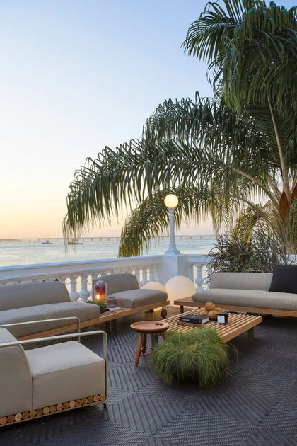 Terraza frente al mar con sofás blancos y palmeras al atardecer — proyecto Casa COR 2019, por Studio Ro-ca