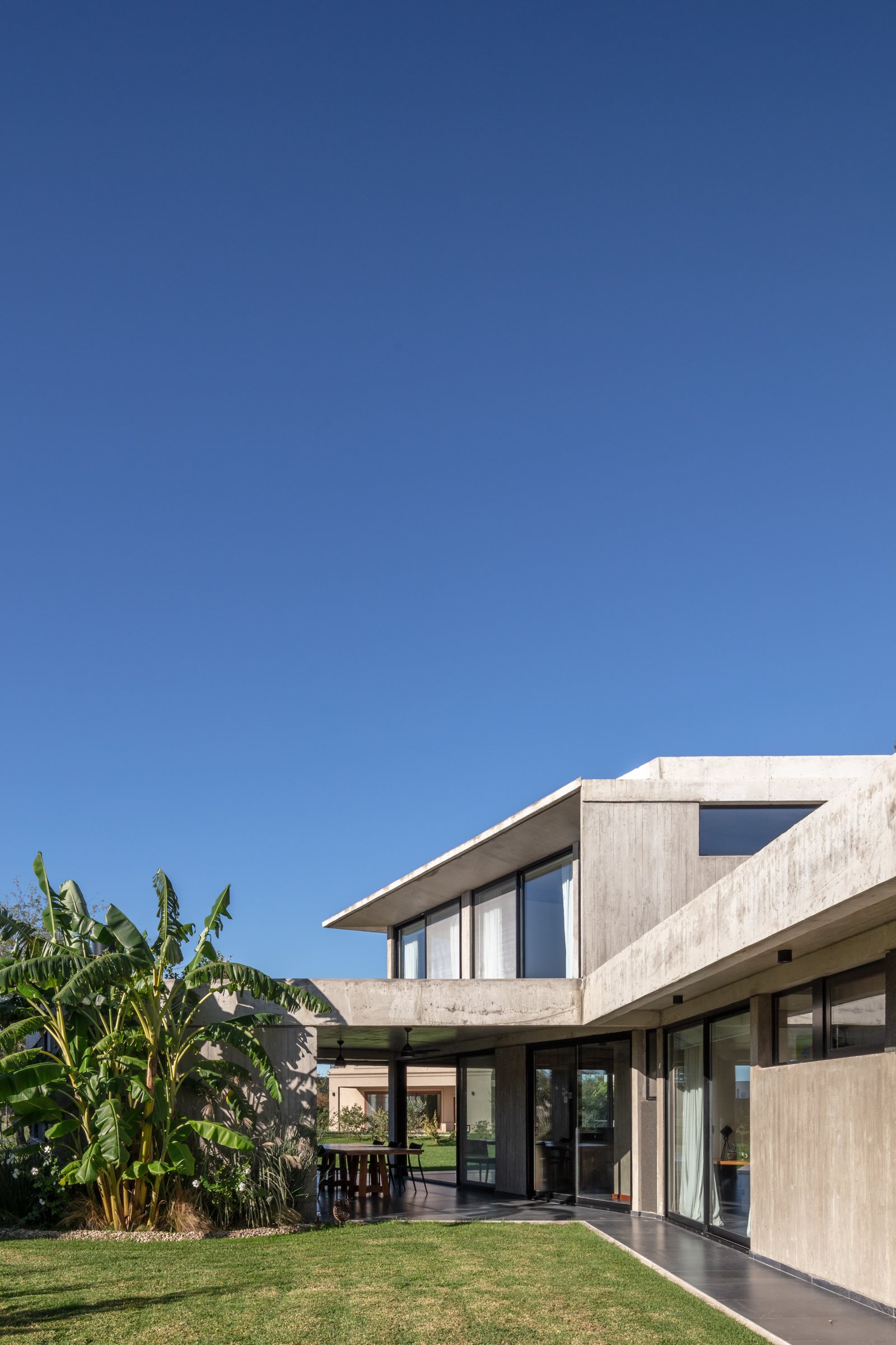 casa moderna brutalista con hormigón expuesto y mucha vegetación — proyecto La Martona UF280, por BARBALACO ARQUITECTOS, en Provincia de Buenos Aires
