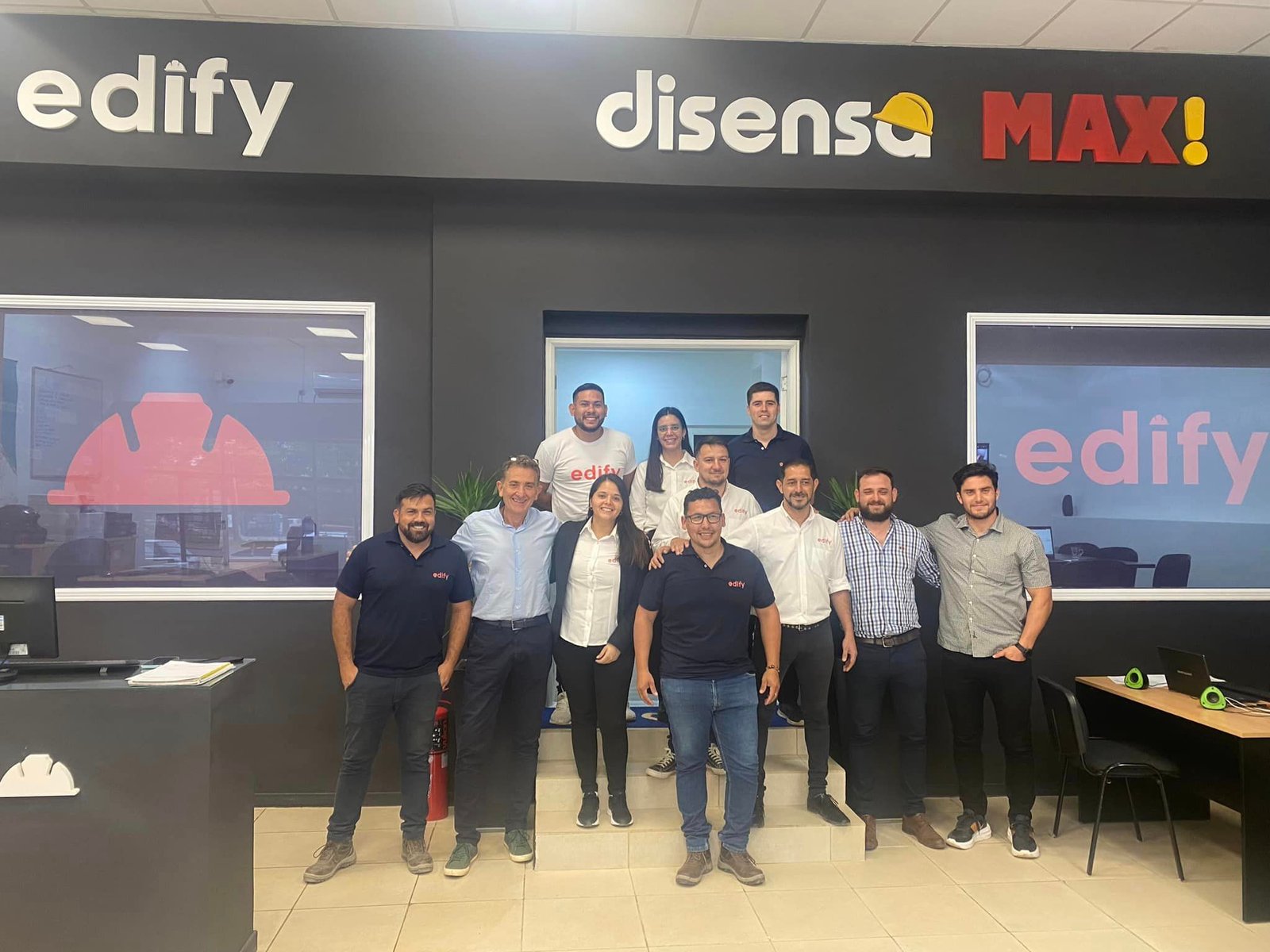Grupo de pessoas em escritório moderno com logos iluminados — projeto Edify Posadas, por Arquitecto Gustavo Maidana, em Posadas