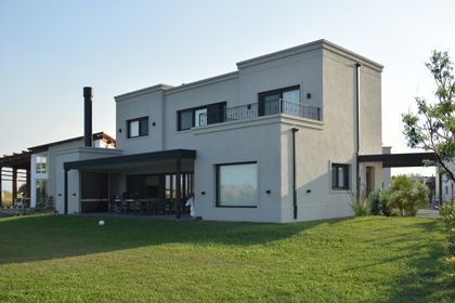 Casa moderna de dos pisos con amplios ventanales y patio exterior — proyecto Casa CG191, por EZ architects, en Belén de Escobar