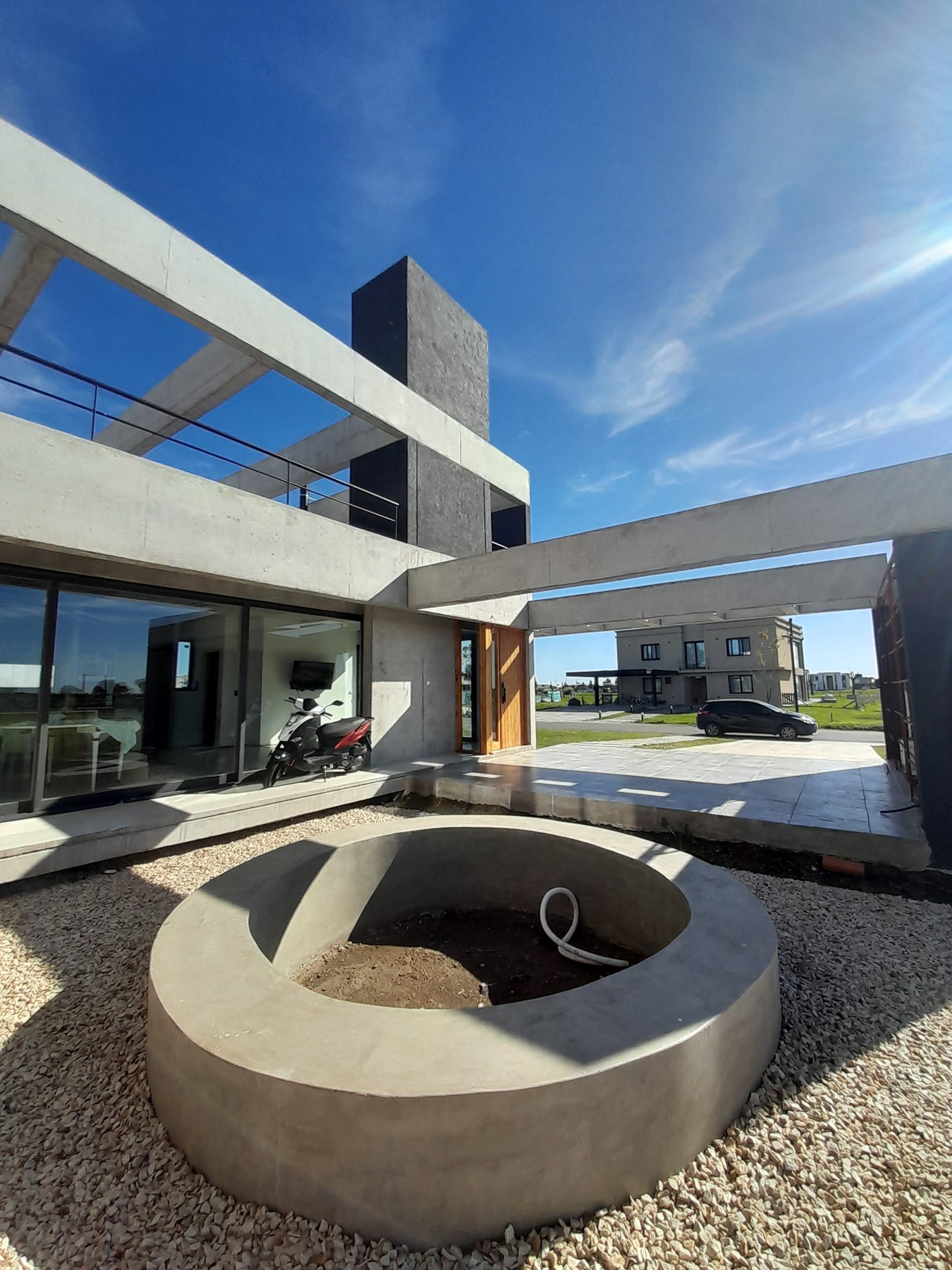 Fachada moderna com vigas de concreto e fogueira redonda — projeto Puerto Nizuc, por Estudio Fernandez Long & asoc., em Au Dr. Ricardo Balbín km 31.5