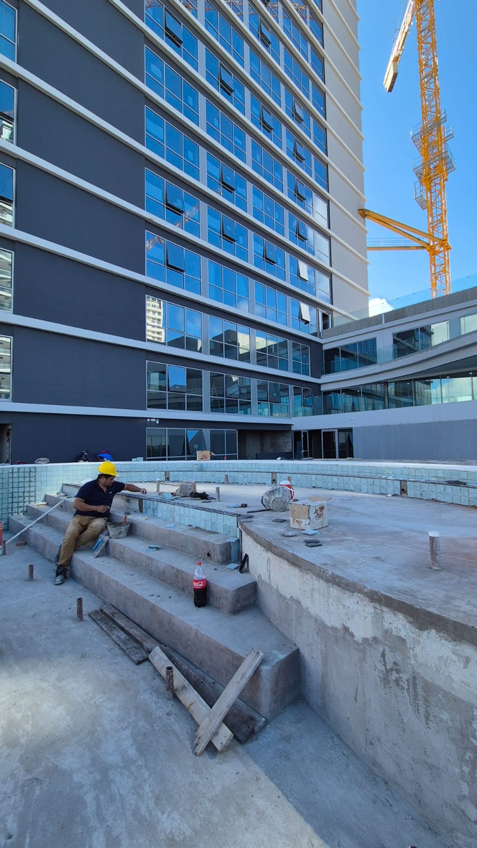 obra de pileta moderna junto a edificio con worker — proyecto Obra Piscina Los Boulevares Corrientes en Proceso, por Aquamare Piscinas, en Corrientes