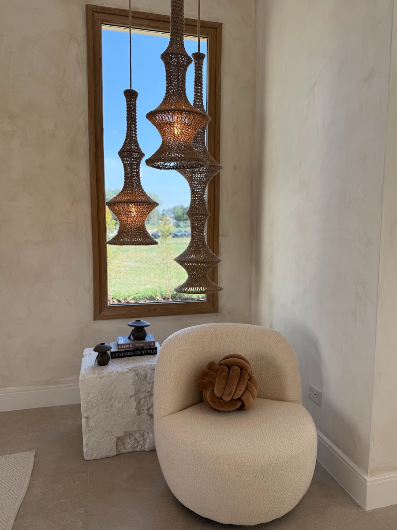 Living con sillón off-white, luces de mimbre y mesa de piedra — proyecto La Verbena, por Grupo Pauta Arquitectura, en Alejandro Korn 3150