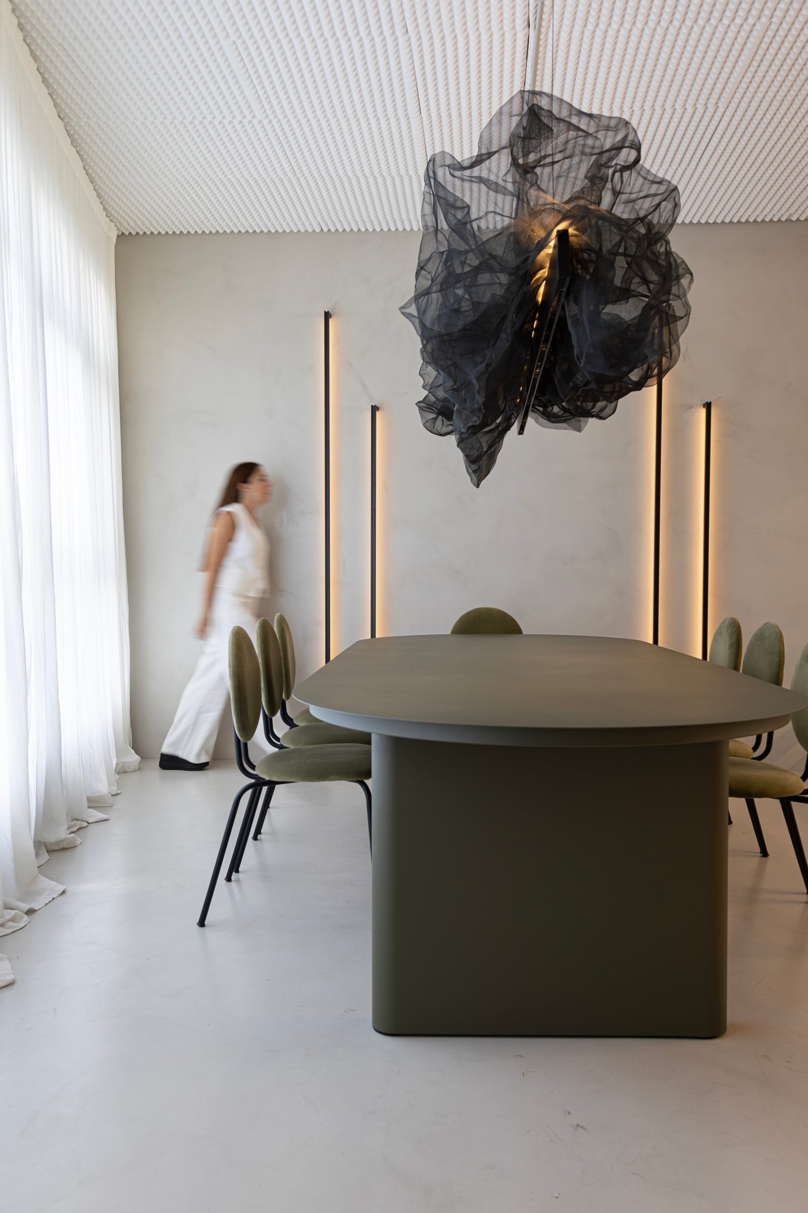 Comedor moderno con mesa trapezoidal verde y lámpara colgante abstracta — proyecto HATSU Núñez - MZV Arquitectura, por Gaby Alfonso, en Buenos Aires