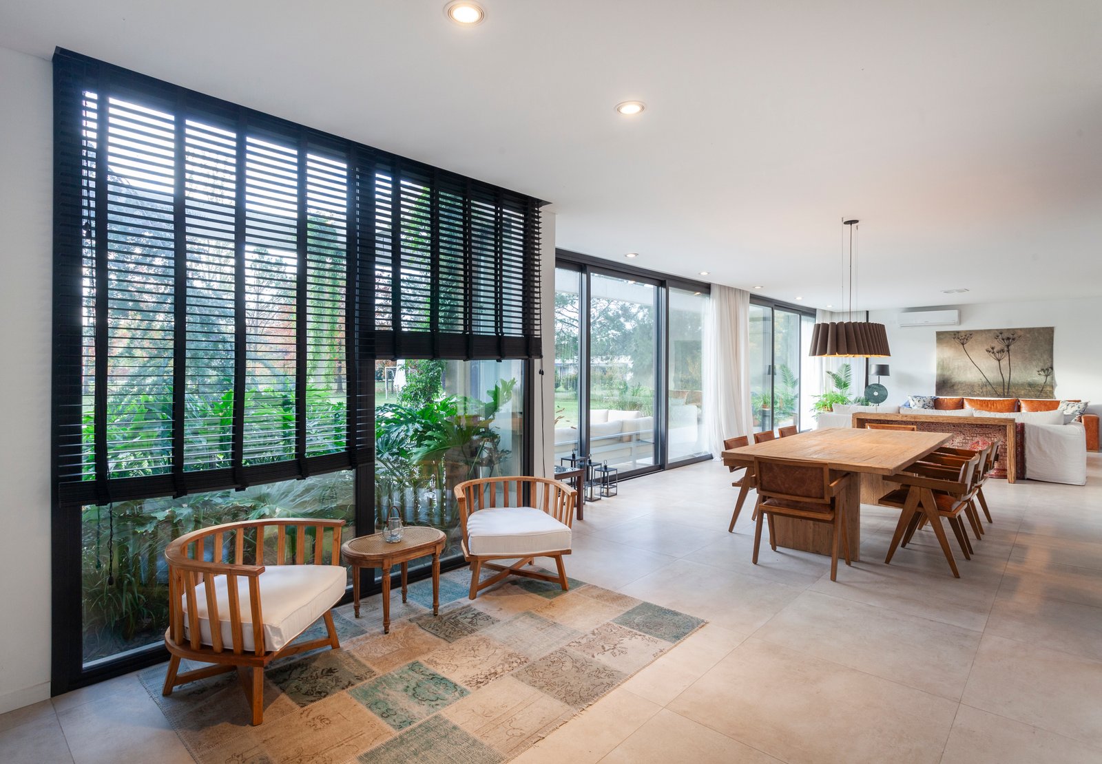 Living comedor moderno con grandes ventanales y muebles de madera y rattan — proyecto CASA HS143, por A'PRIMA - Arquitectura Sustentable, en km 7.5 Ruta 25