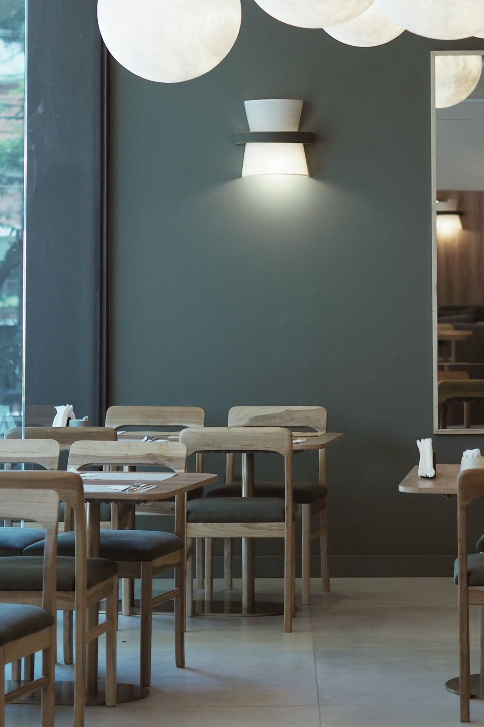 sala de jantar moderna com cadeiras de madeira e luzes esféricas — projeto FOMO CAFÉ, por APATHEIA, em Vicente López