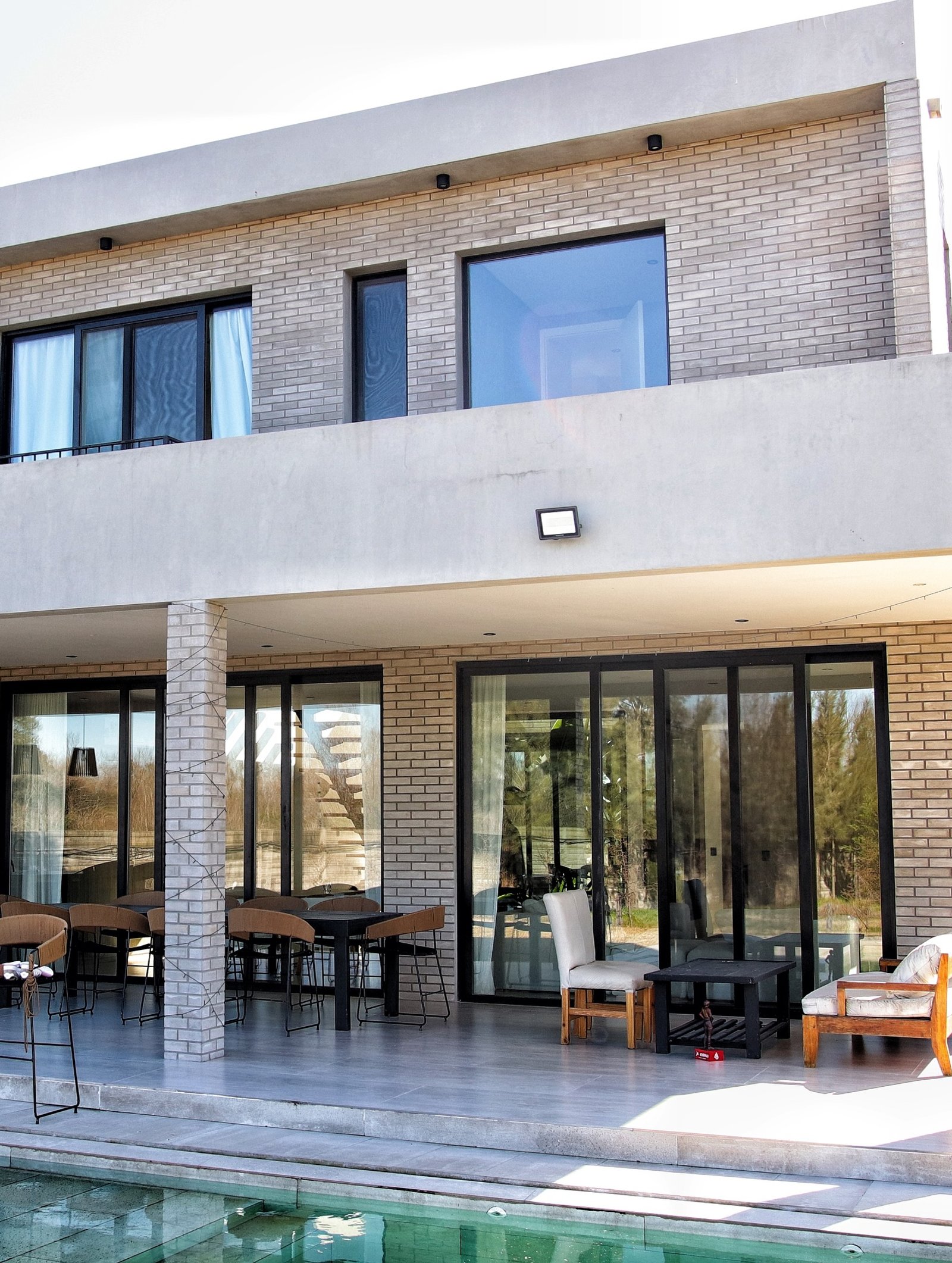 Casa moderna com piscina, tijolos aparentes e janelas do chão ao teto — projeto FILMS 3M de control Solar, Seguridad y Privacidad, por Grupo Laminar