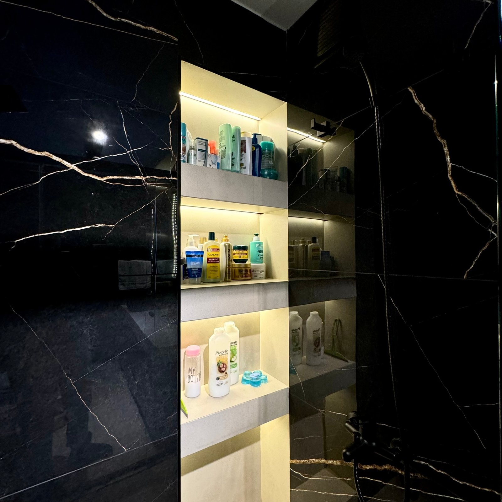 Banheiro moderno com paredes de mármore preto e prateleiras iluminadas — projeto Coronel Diaz, por MDBK Arquitectura, em Palermo
