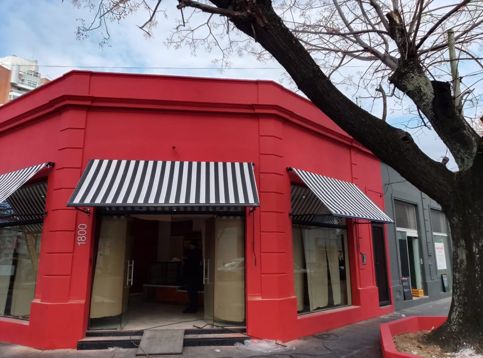 Fachada roja moderna con toldo a rayas — proyecto Toldos Punto Recto, por ToldosYa