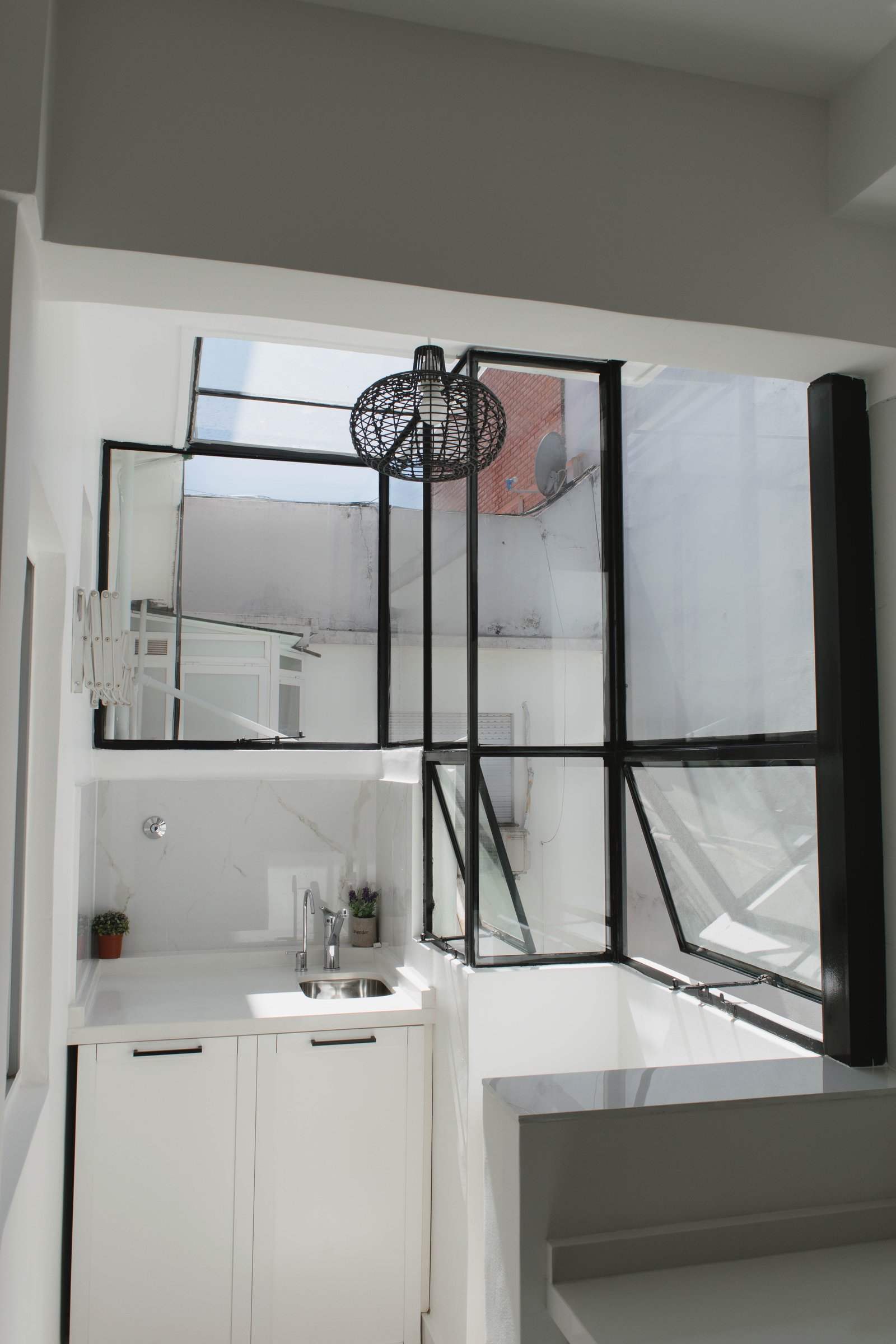 Cocina moderna de doble altura con grandes ventanales industriales — proyecto Goyena, por Martina Kleinert, en Caballito