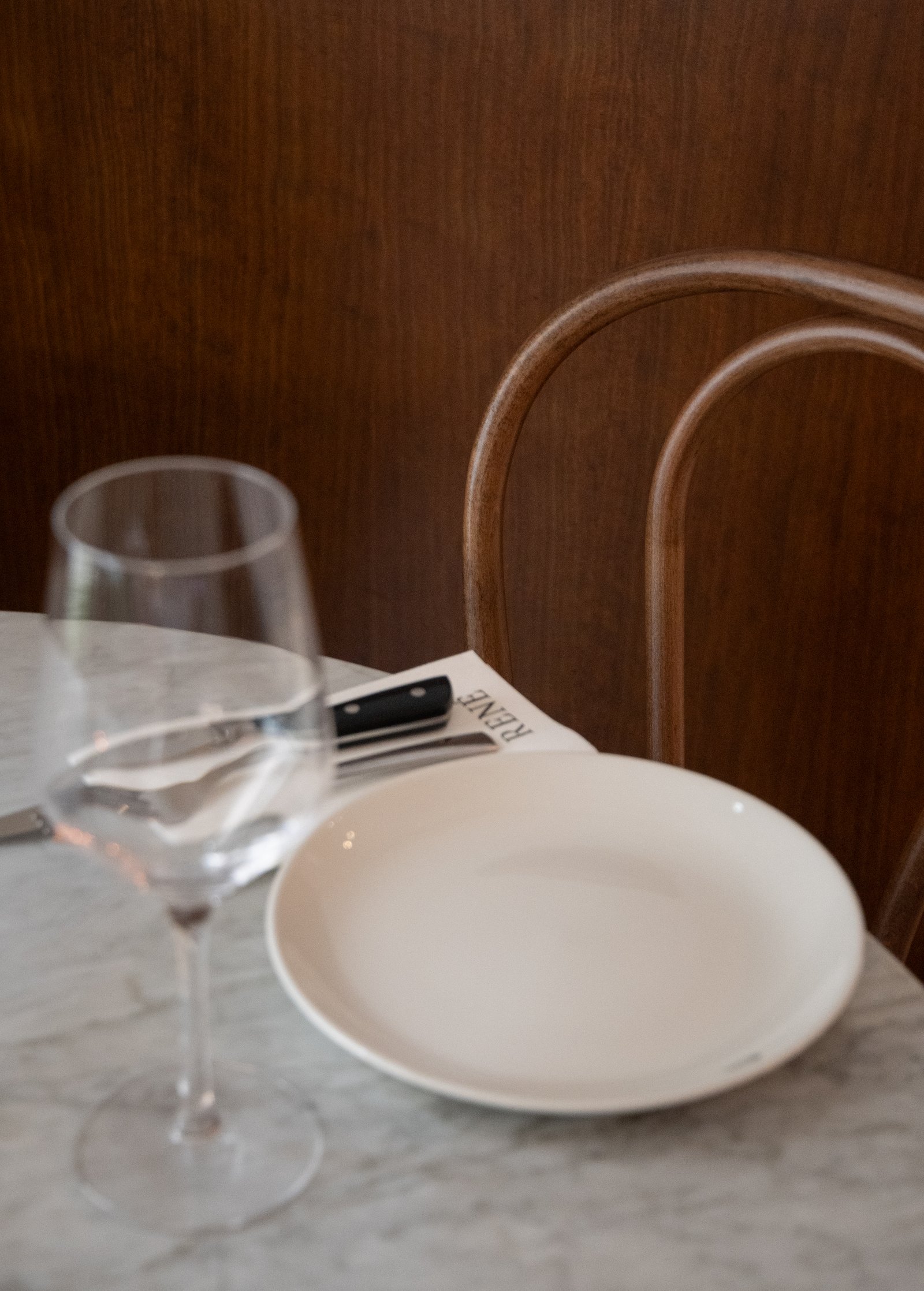 mesa de comedor con copa de vino y plato — proyecto René Restaurant, por JT ARQUITECTURA, en Valencia