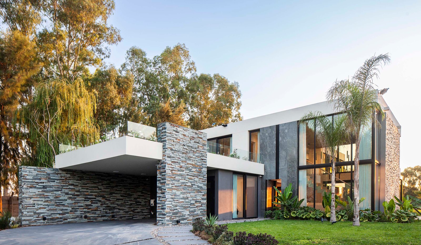 Fachada moderna com volumes geométricos e revestimento em pedra — projeto CASA T199, por A'PRIMA - Arquitectura Sustentable, em Los Robles 5901