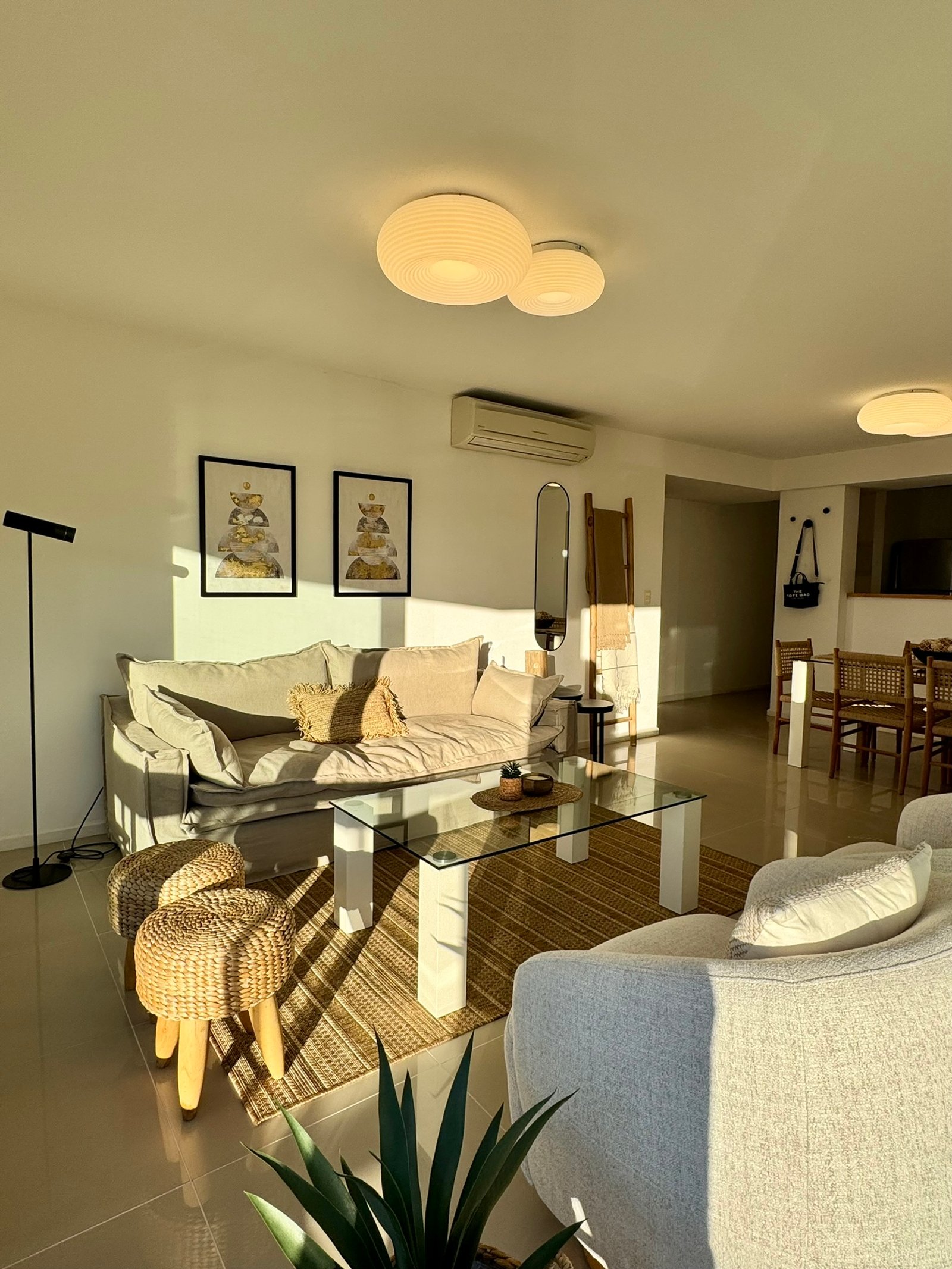 Living moderno con luz dorada, sofá de tela y mesa de centro de vidrio — proyecto Quartier Punta del Este, por MDBK Arquitectura, en Punta del Este