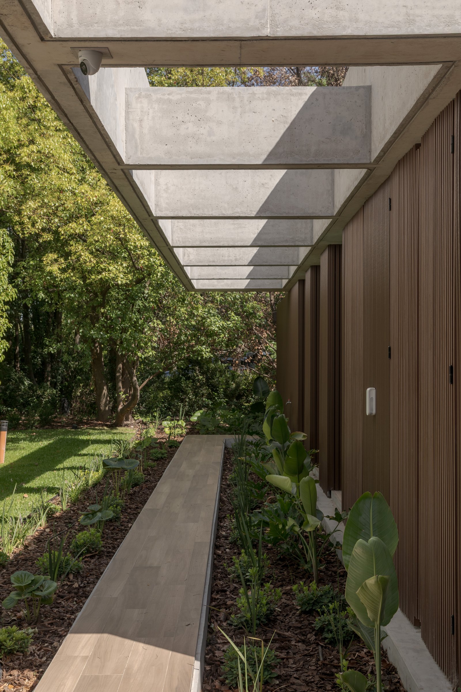 Pergola de hormigón y camino en jardín exuberante — proyecto Casa PLANALTO, por Grupo CRBN, en Av. Pres. Perón 10298