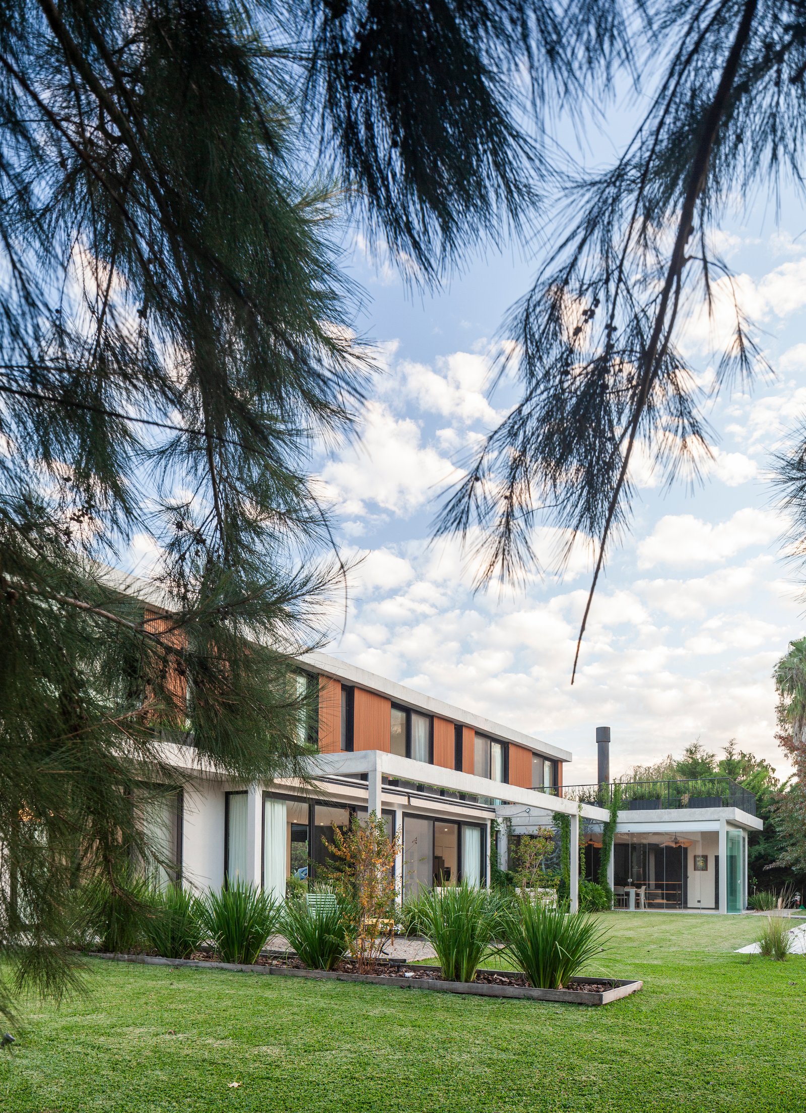 Casa moderna con fachada de ladrillo y pinos — proyecto CASA HS143, por A'PRIMA - Arquitectura Sustentable, en km 7.5 Ruta 25