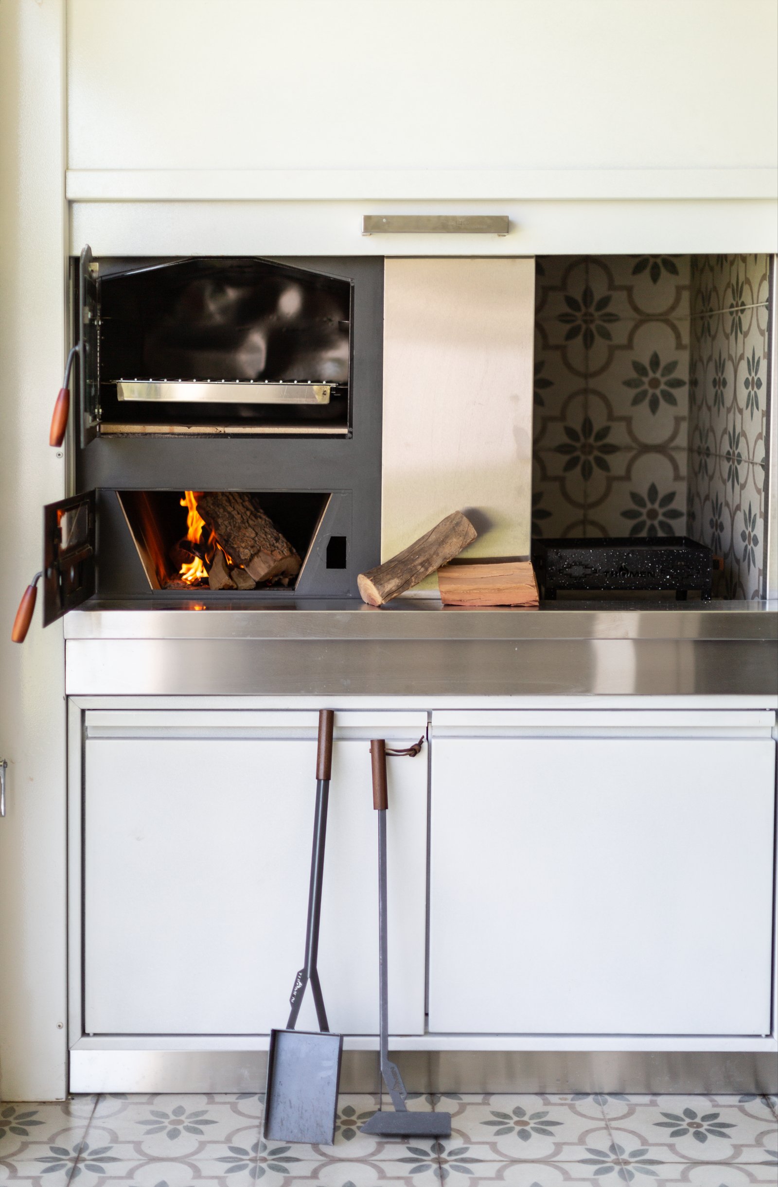 Quincho moderno con horno empotrado, azulejos decorativos y herramientas de parrilla — proyecto Galeria, por CASA1-TROMEN, en Bella Vista