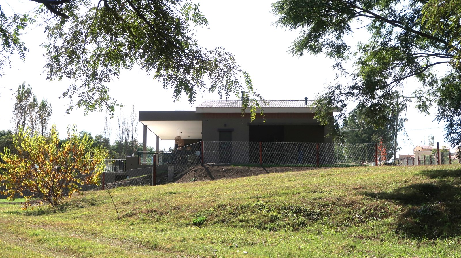 Fachada moderna con amplios ventanales en entorno rural — proyecto Casa La Paz, por Luciana González Anderson, en Salta