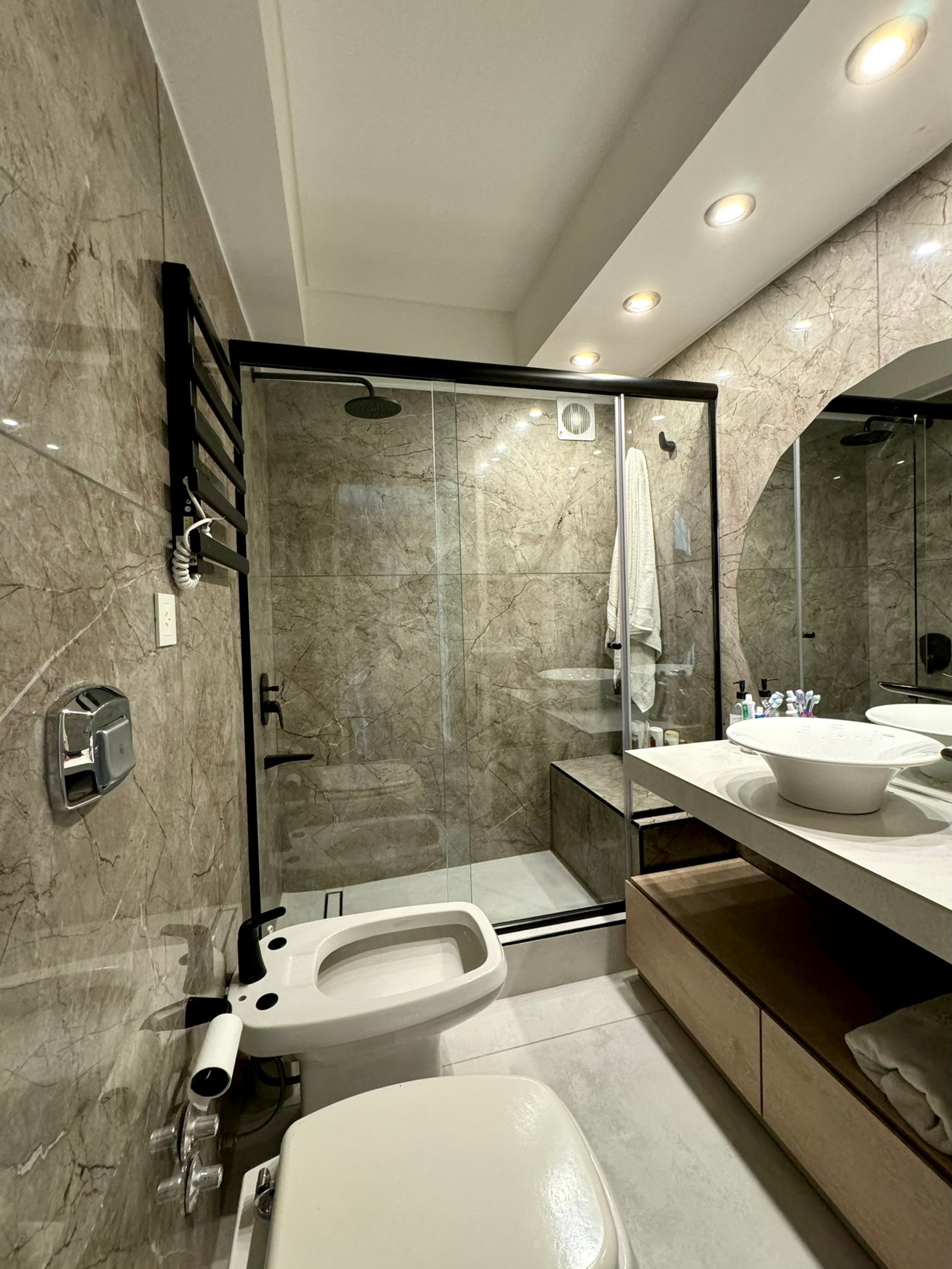Baño moderno con paredes de mrmol, ducha de vidrio y vanitory de madera — proyecto Coronel Diaz, por MDBK Arquitectura, en Palermo