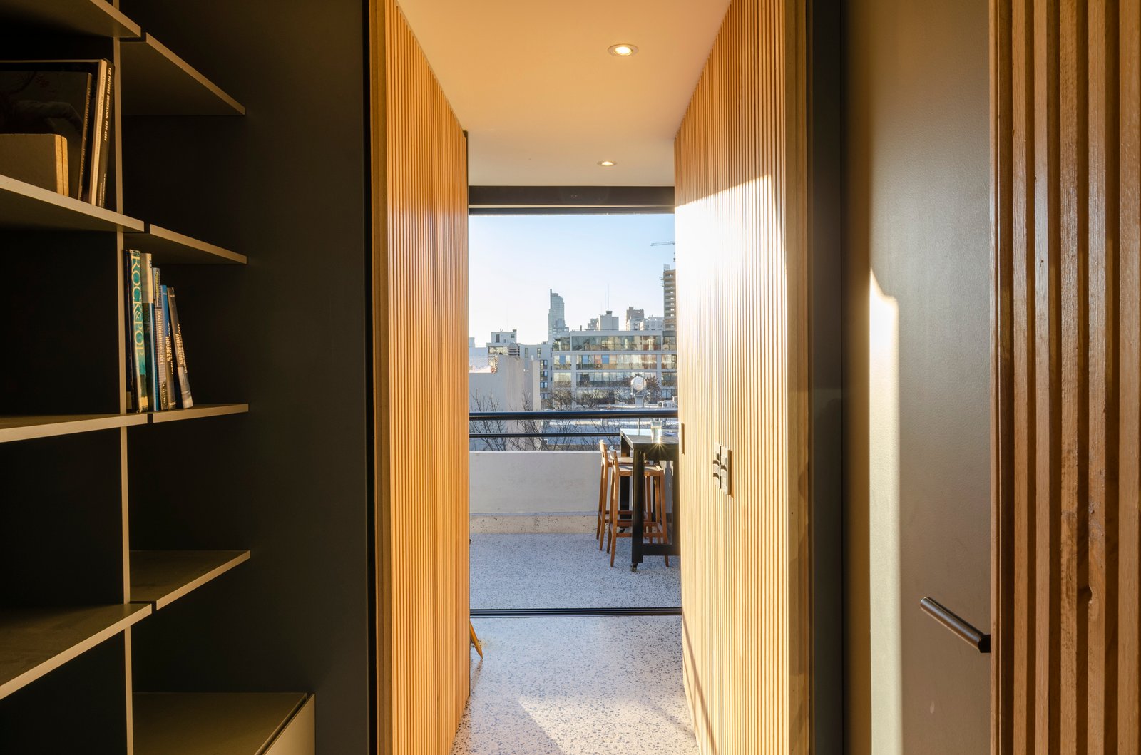 pasillo moderno con revestimiento de madera y balcón urbano — proyecto Guayra - Andrea Gonzales, por ABEJA CONCEPT, en Belgrano