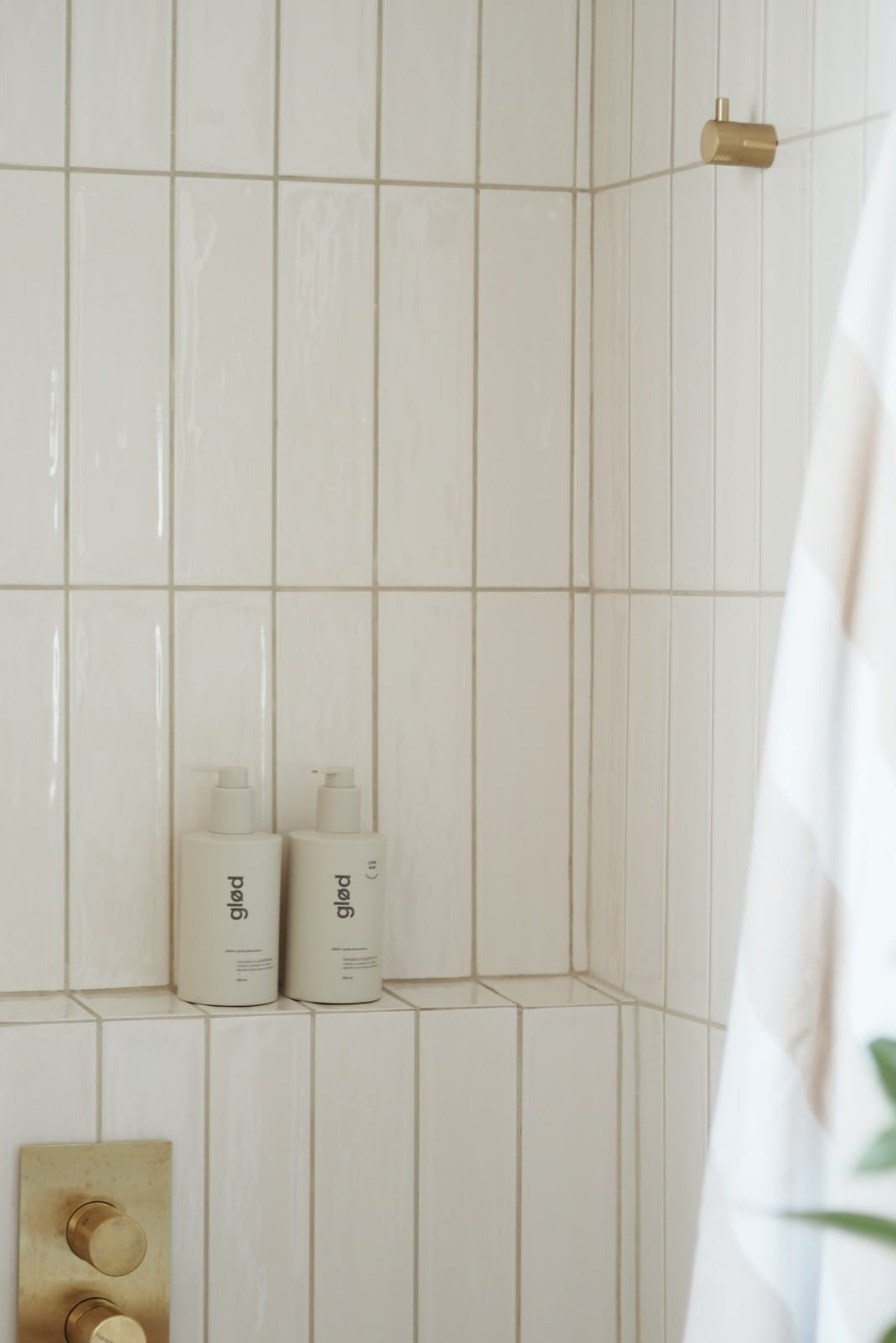 Baño moderno con azulejos blancos verticales, botellas minimalistas y detalles de latón — proyecto MONTEVIDEO , por APATHEIA, en Buenos Aires
